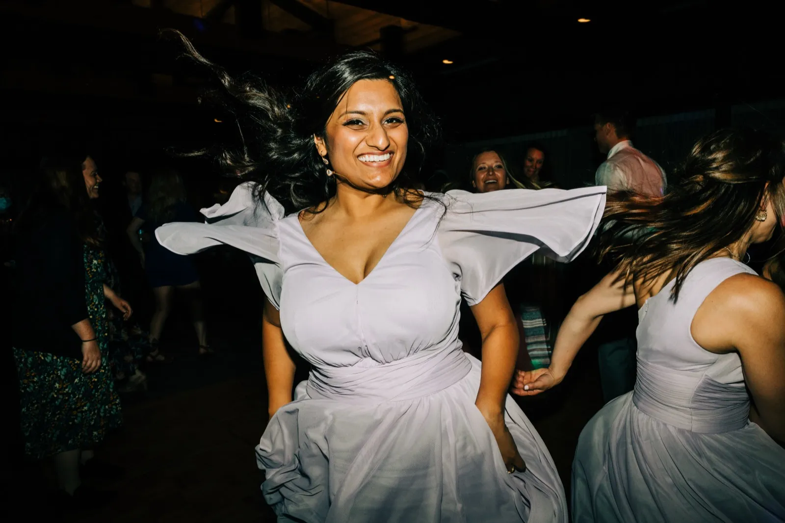 A bridesmaid in lavender laughs mid-spin on the dance floor, her hair flying — Tim Larsen Photography, Brainerd Lakes MN