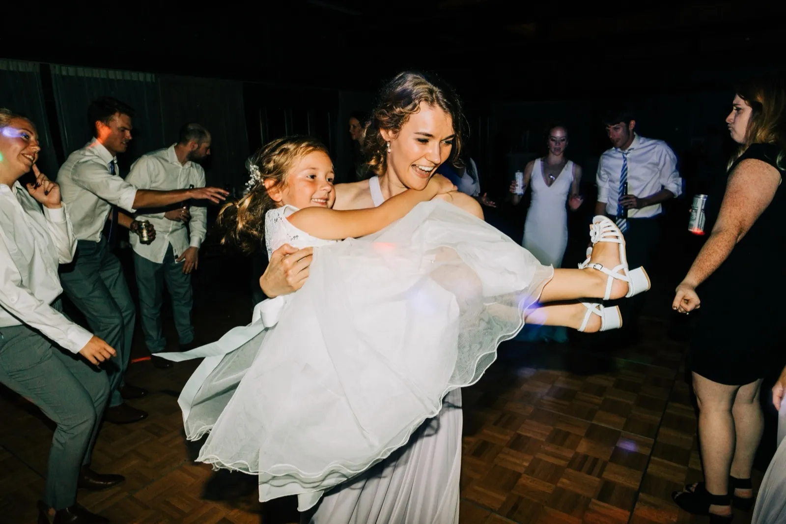 Katie laughs as she lifts and spins a flower girl off the dance floor while guests dance around them — Tim Larsen Photography, Brainerd Lakes MN