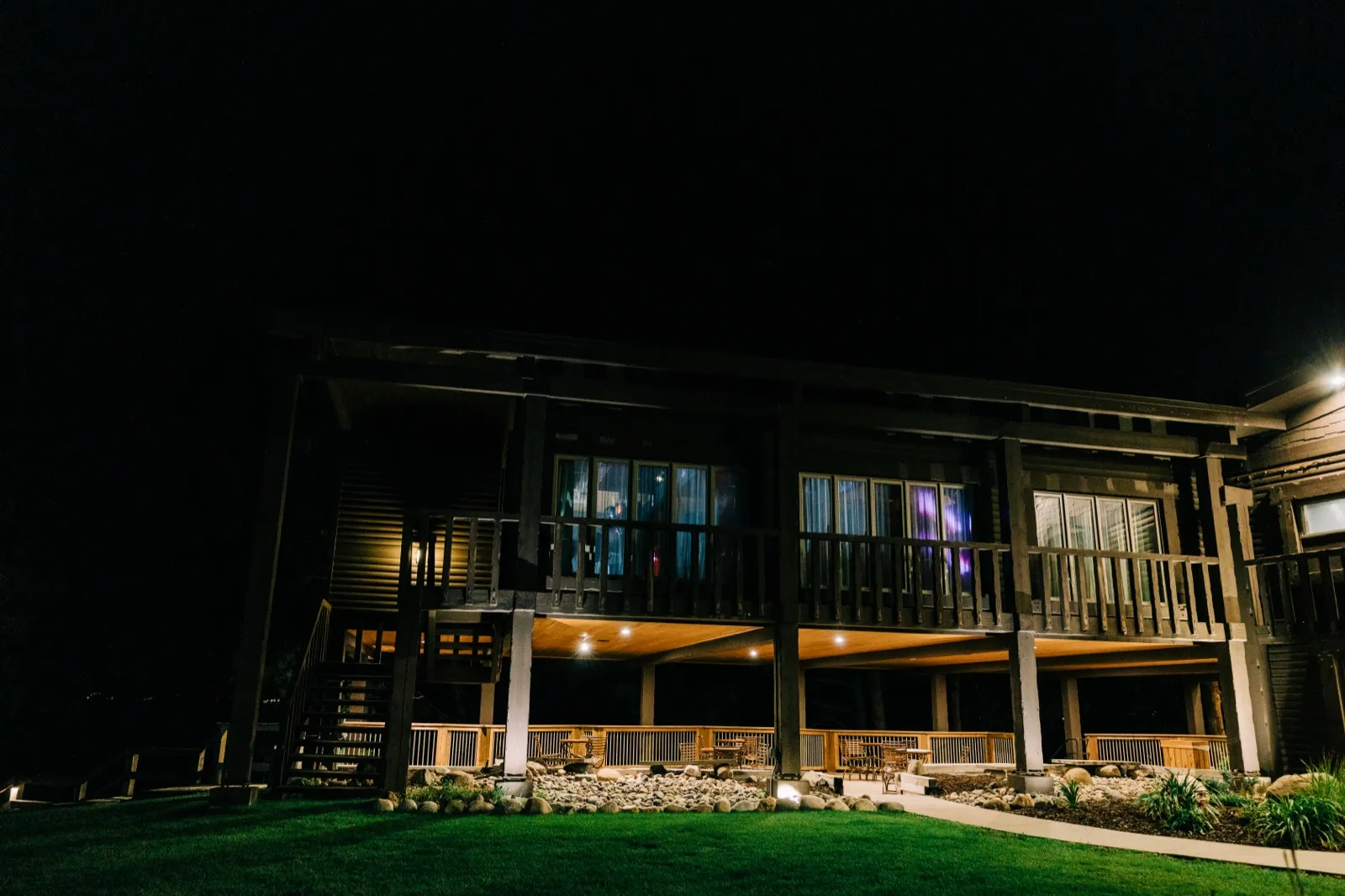 The lodge at Madden's on Gull Lake glows from its covered porch and upper windows above a dark lawn at night — Tim Larsen Photography, Brainerd Lakes MN