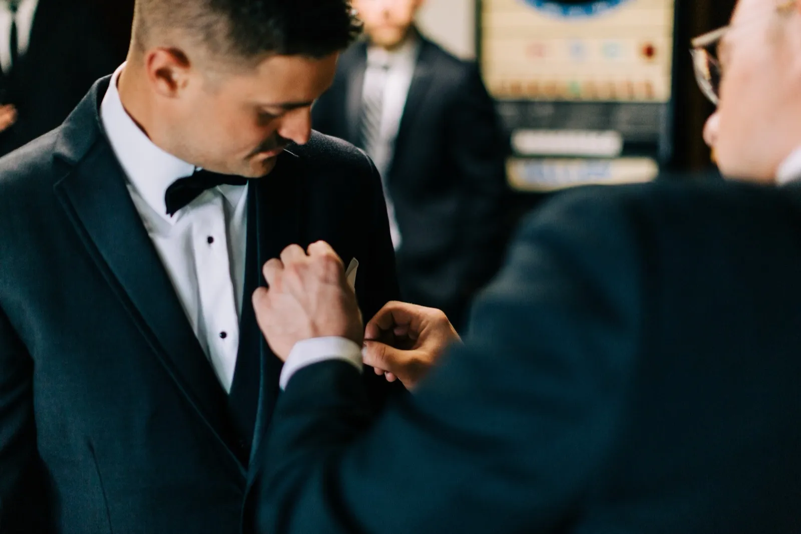A groomsman pins Jonathon's boutonniere to his lapel before the ceremony — Tim Larsen Photography, Brainerd Lakes MN
