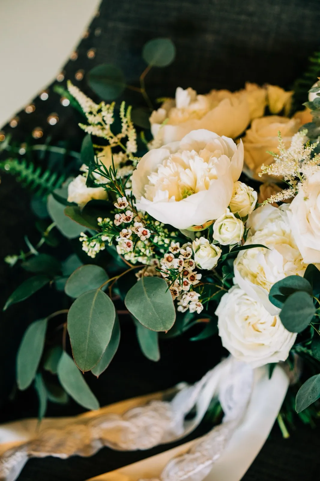 An overhead view of Hailee's white peony, garden rose, and eucalyptus bouquet resting on her beaded gown — Tim Larsen Photography, Brainerd Lakes MN