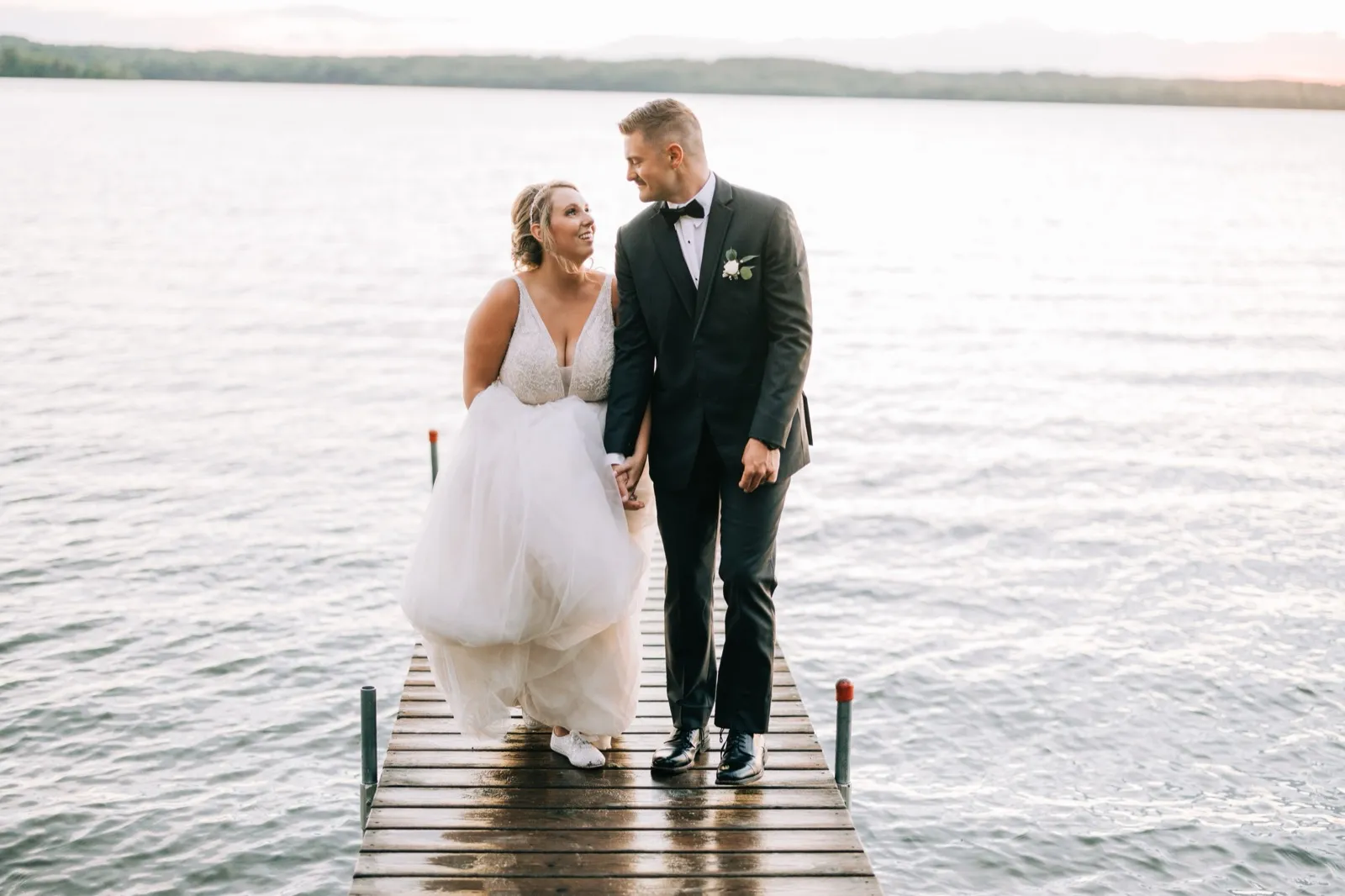 Hailee and Jonathon hold hands walking down a long dock over Gull Lake at sunset — Tim Larsen Photography, Brainerd Lakes MN