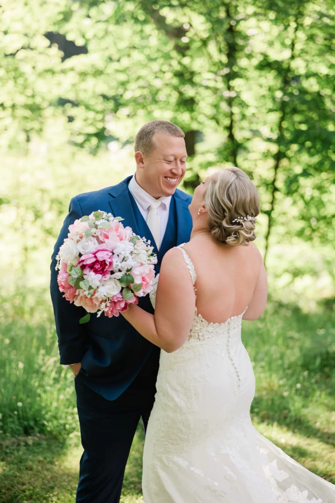 Bride and groom stand face to face laughing in the sunlit woods just after their first look — Tim Larsen Photography, Brainerd Lakes MN