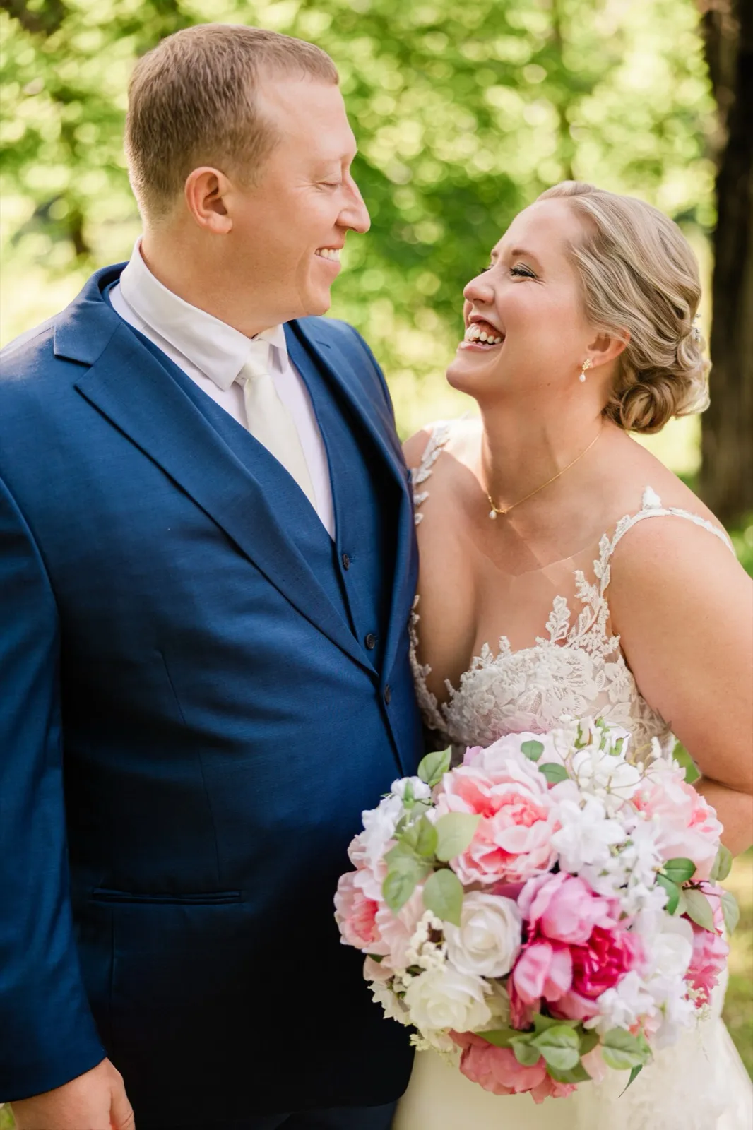 Lauren and Jeremy laugh face-to-face in a wooded clearing, her large pink-and-white bouquet between them — Tim Larsen Photography, Brainerd Lakes MN