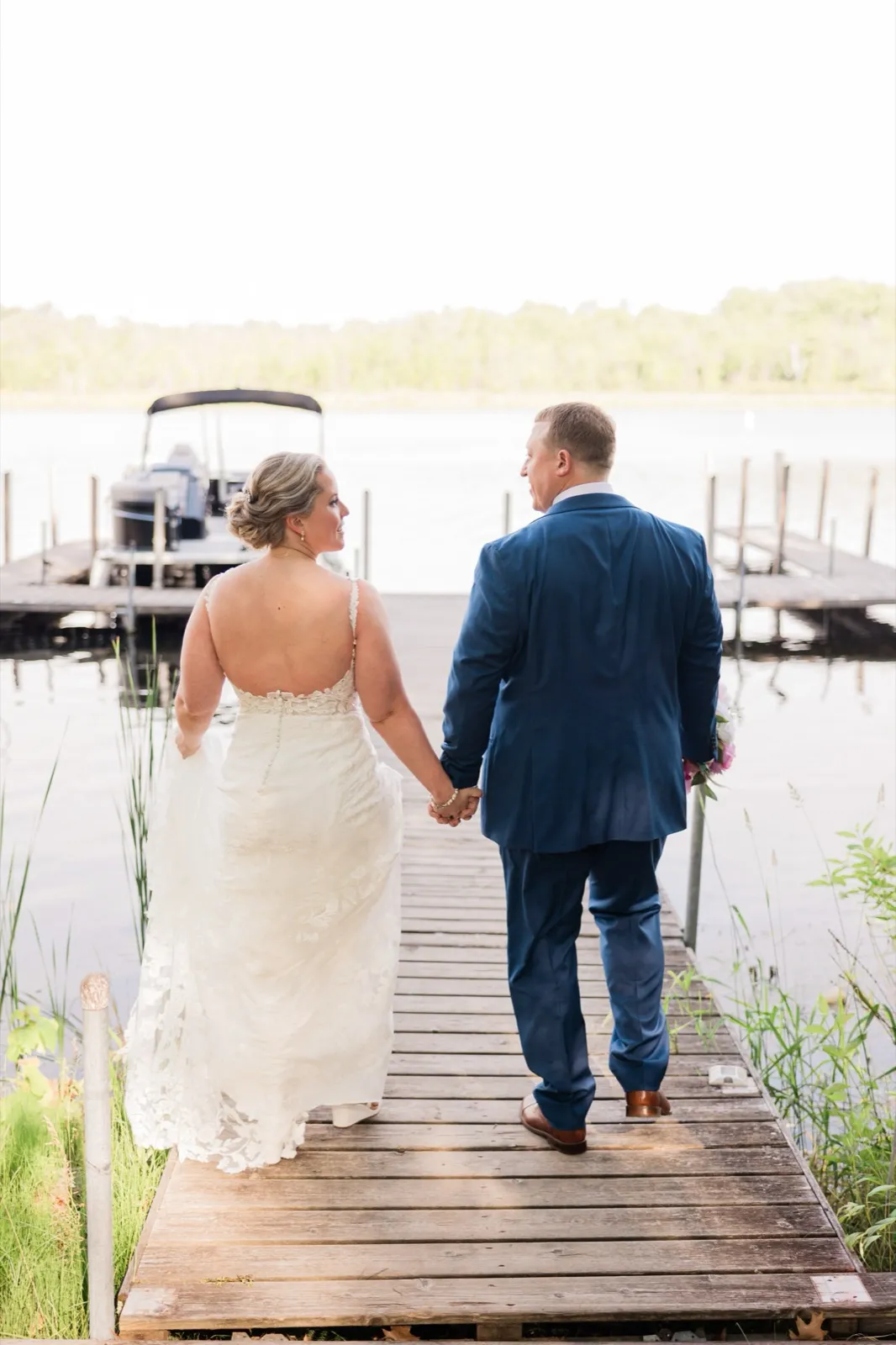 Bride and groom walk away hand-in-hand down the dock at Lost Lake Lodge toward open water — Tim Larsen Photography, Brainerd Lakes MN