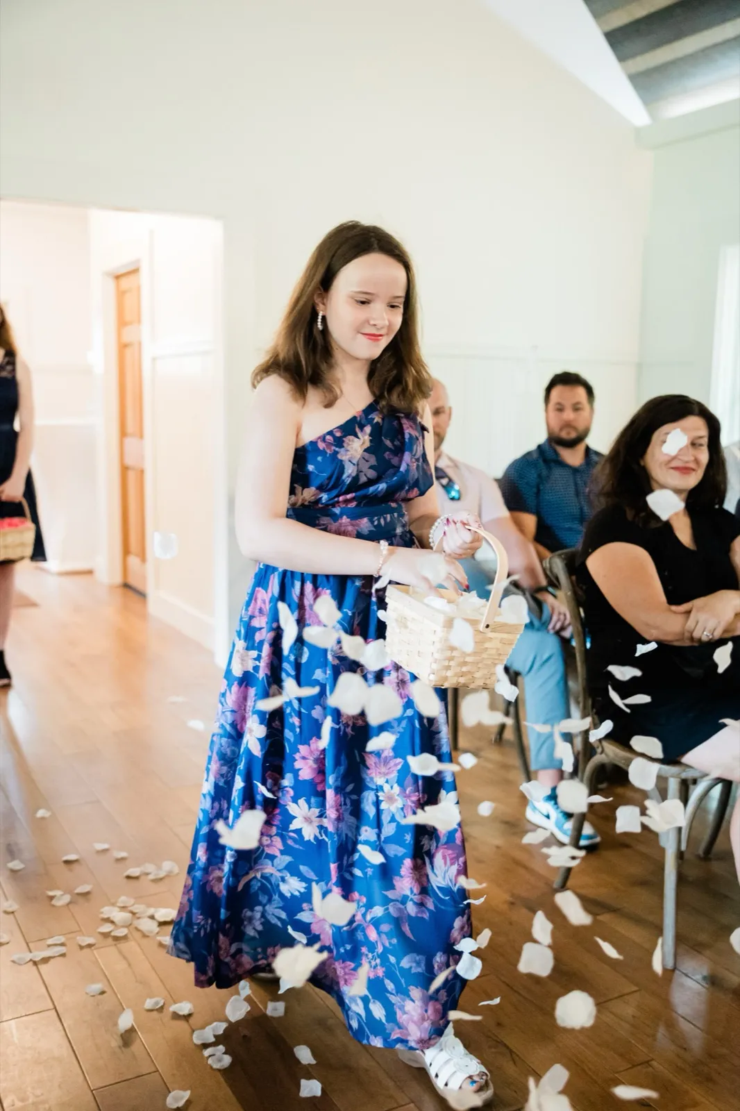 The flower girl scatters white petals that hang suspended in the air as guests watch her come down the aisle — Tim Larsen Photography, Brainerd Lakes MN