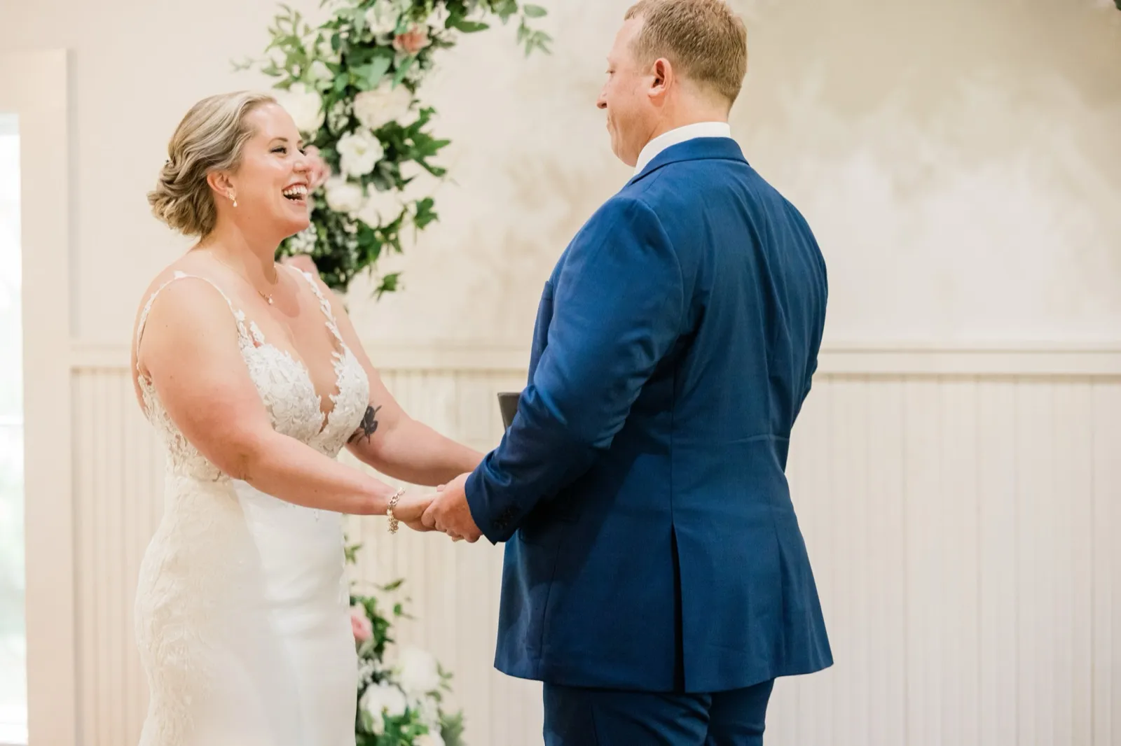 Lauren laughs holding Jeremy's hands at the altar during the ceremony — Tim Larsen Photography, Brainerd Lakes MN