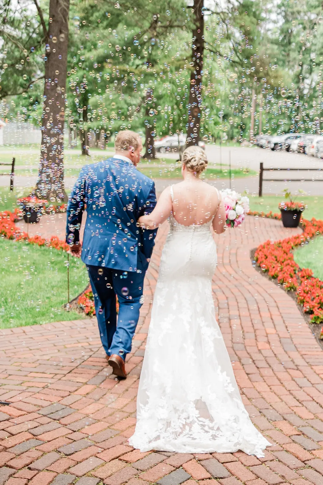 The couple walks away down the brick garden path through a cloud of bubbles outside the chapel — Tim Larsen Photography, Brainerd Lakes MN