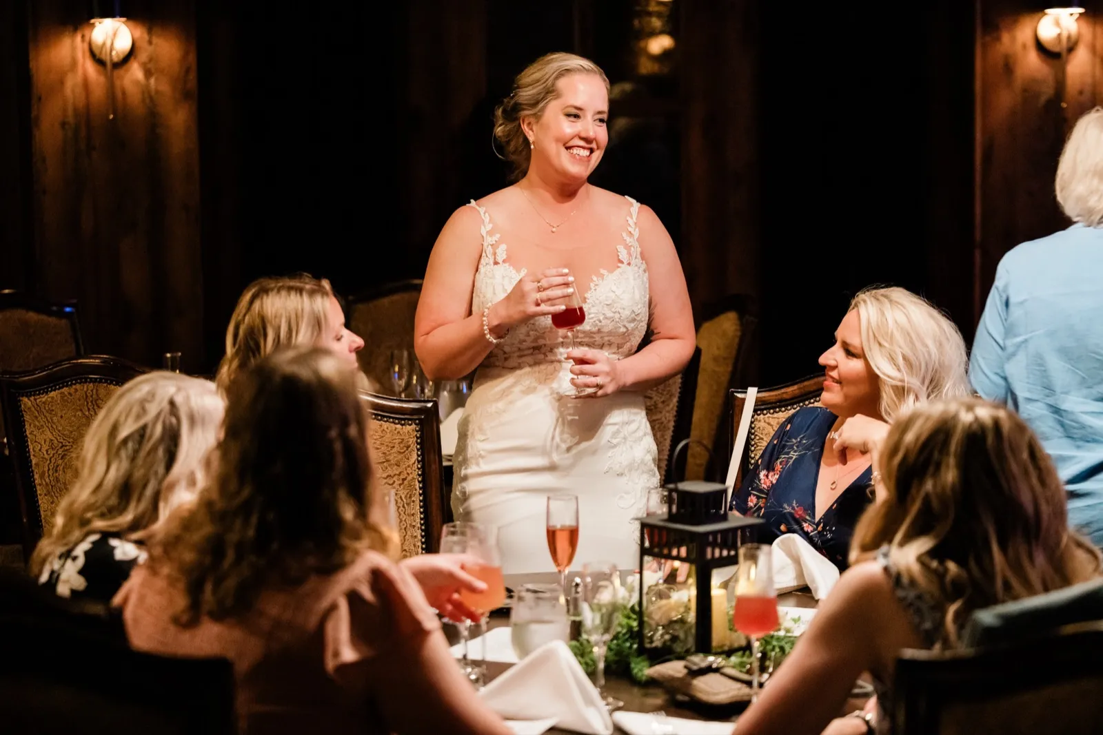 Lauren stands laughing, drink in hand, as friends raise mimosas around a candlelit table at Cru — Tim Larsen Photography, Brainerd Lakes MN