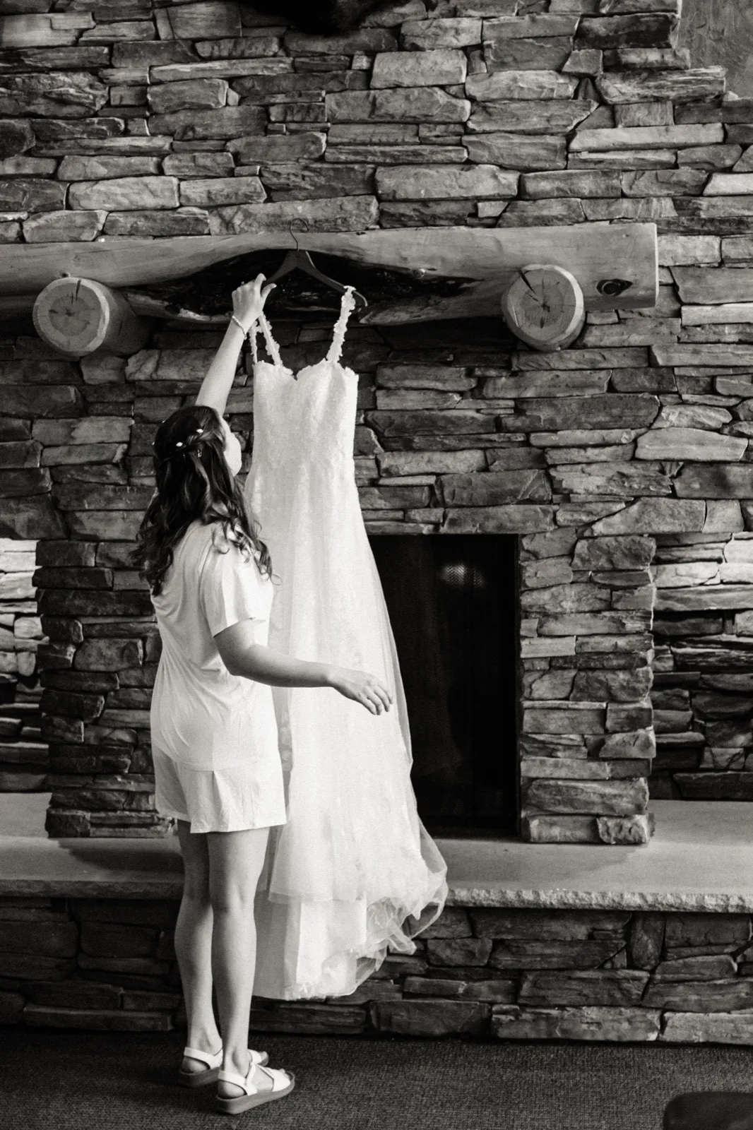 Maddie reaches for her dress beside the stone fireplace at Whitefish Lodge — Tim Larsen Photography, Brainerd Lakes MN
