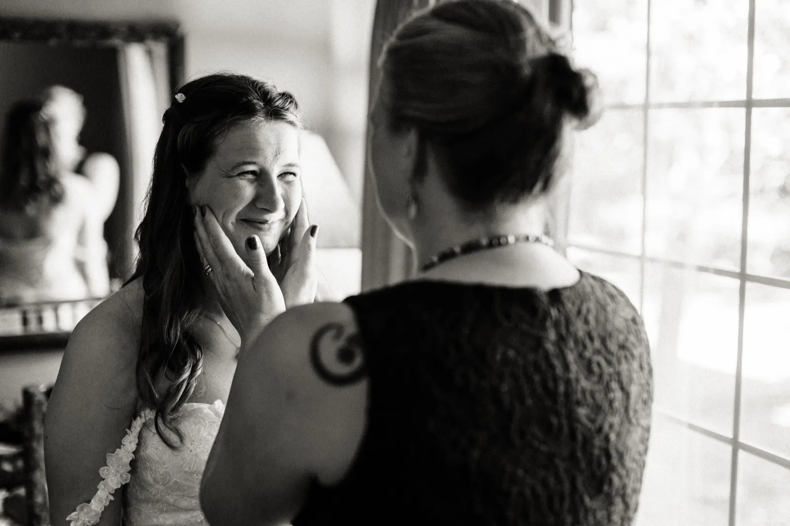 Maddie smiles as a woman cups her cheek beside a bright window in a black-and-white photograph — Tim Larsen Photography, Brainerd Lakes MN