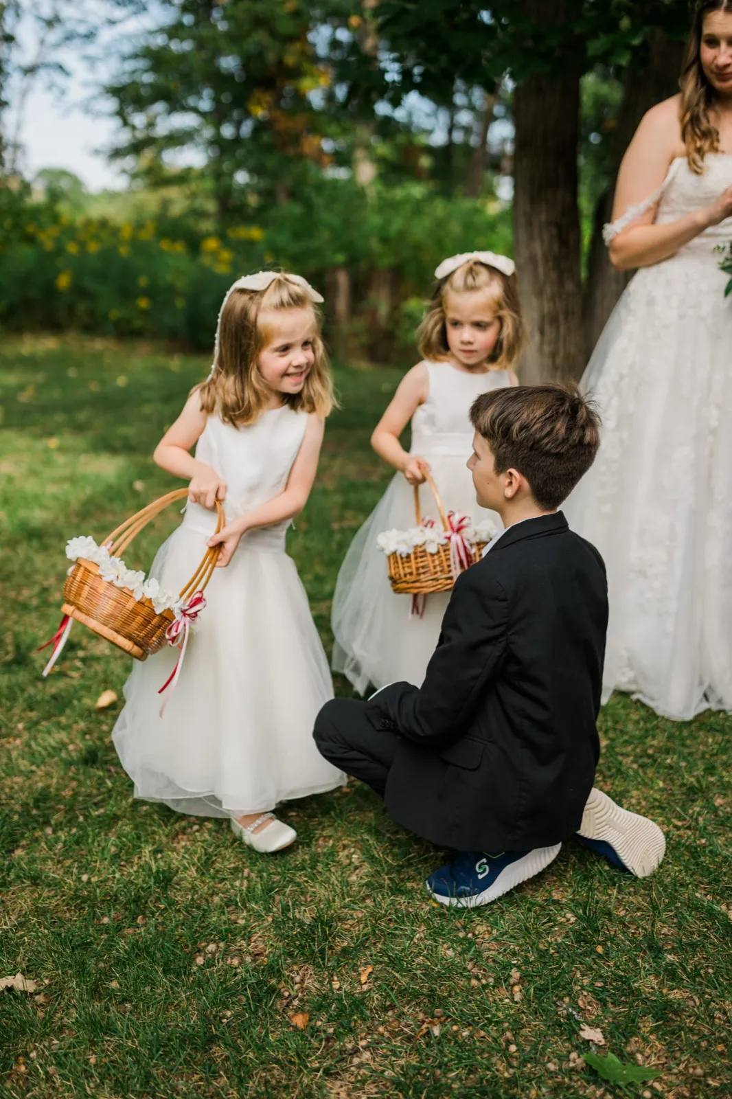 Two flower girls hold petal baskets beside a young boy before the ceremony — Tim Larsen Photography, Brainerd Lakes MN