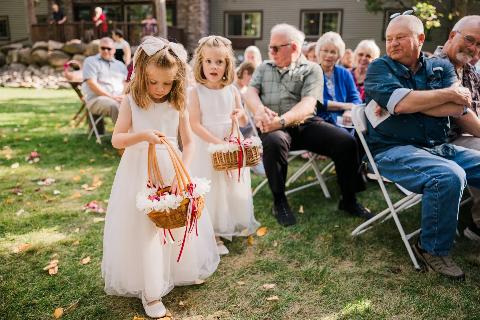 Flower girls scatter petals along the grassy ceremony aisle at Whitefish Lodge — Tim Larsen Photography, Brainerd Lakes MN
