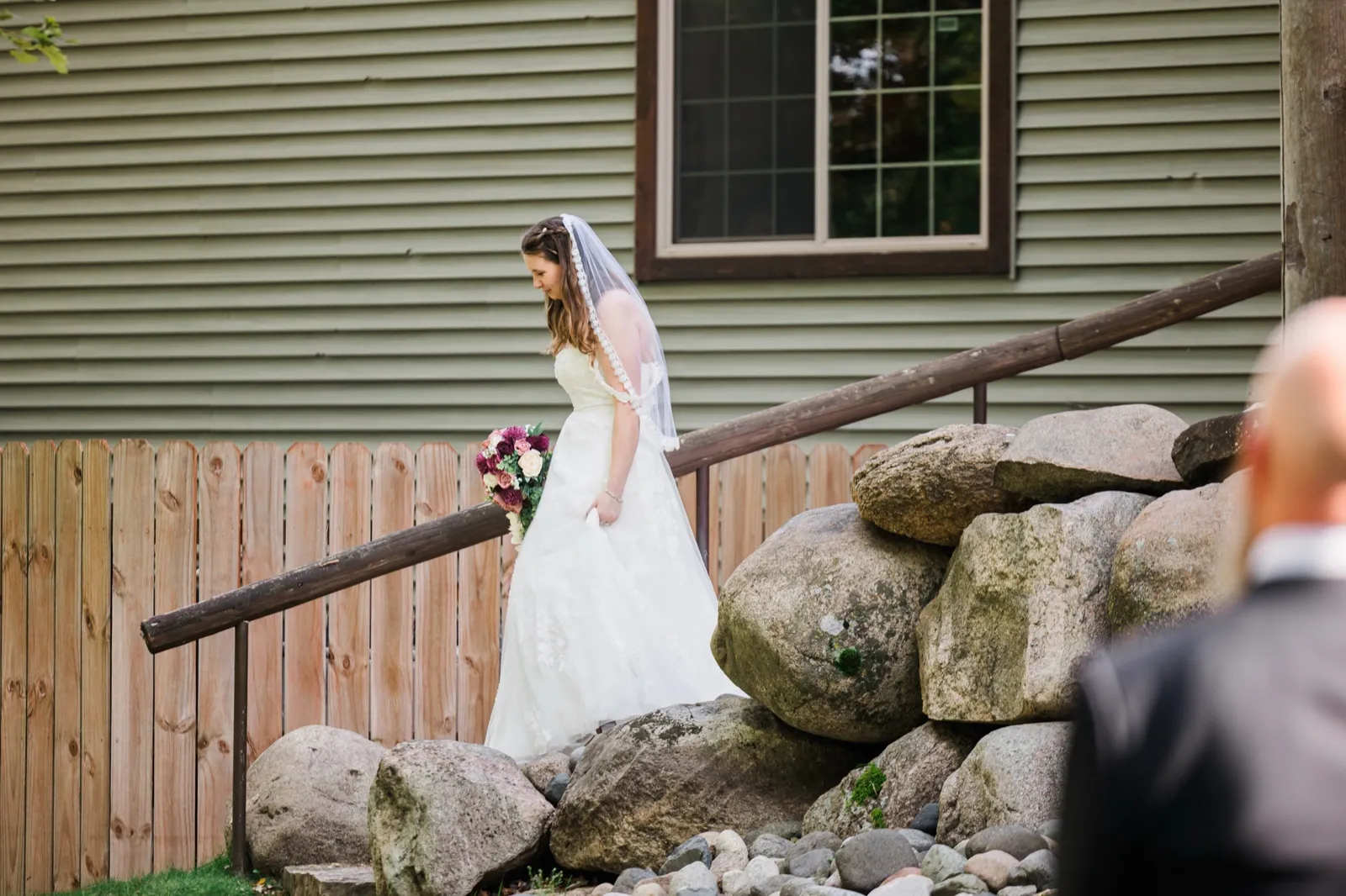 Maddie walks down outdoor stone steps carrying her burgundy and blush bouquet — Tim Larsen Photography, Brainerd Lakes MN