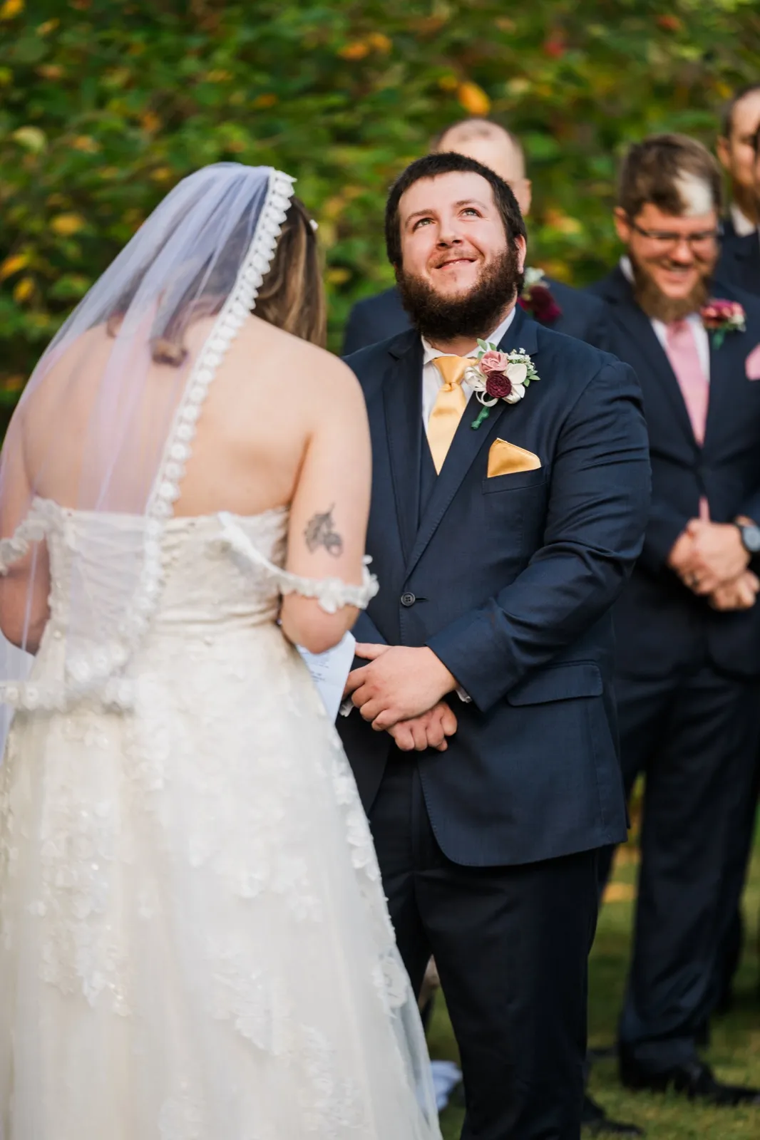Cody looks upward while holding Maddie’s hands during their outdoor ceremony — Tim Larsen Photography, Brainerd Lakes MN
