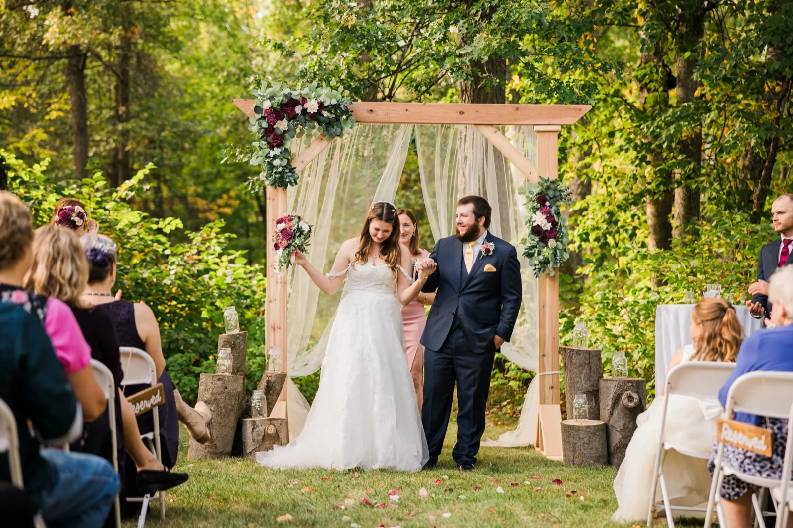 Maddie and Cody walk hand in hand away from their ceremony arch — Tim Larsen Photography, Brainerd Lakes MN