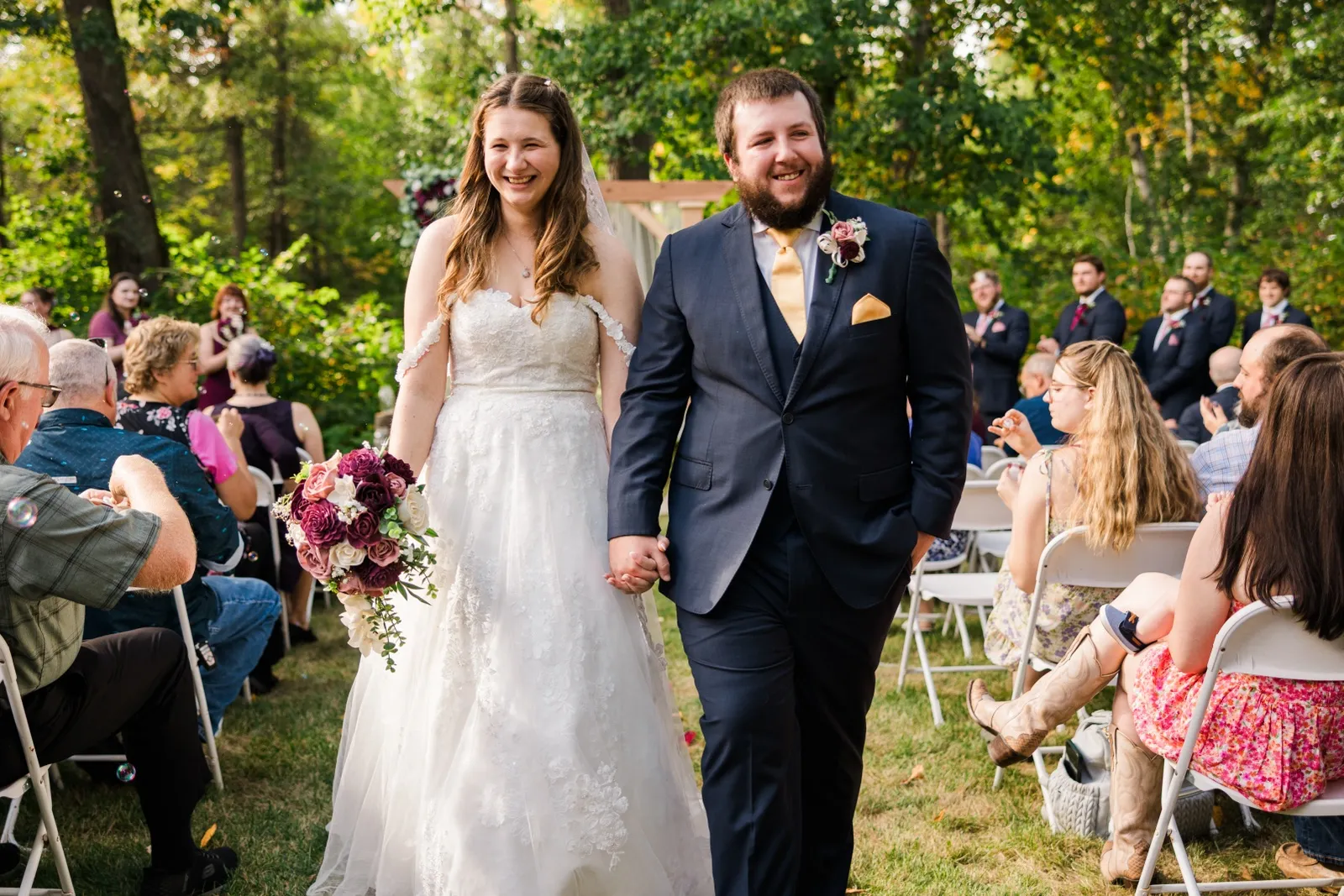 Maddie and Cody walk down the aisle smiling as their guests blow bubbles at Whitefish Lodge — Tim Larsen Photography, Brainerd Lakes MN