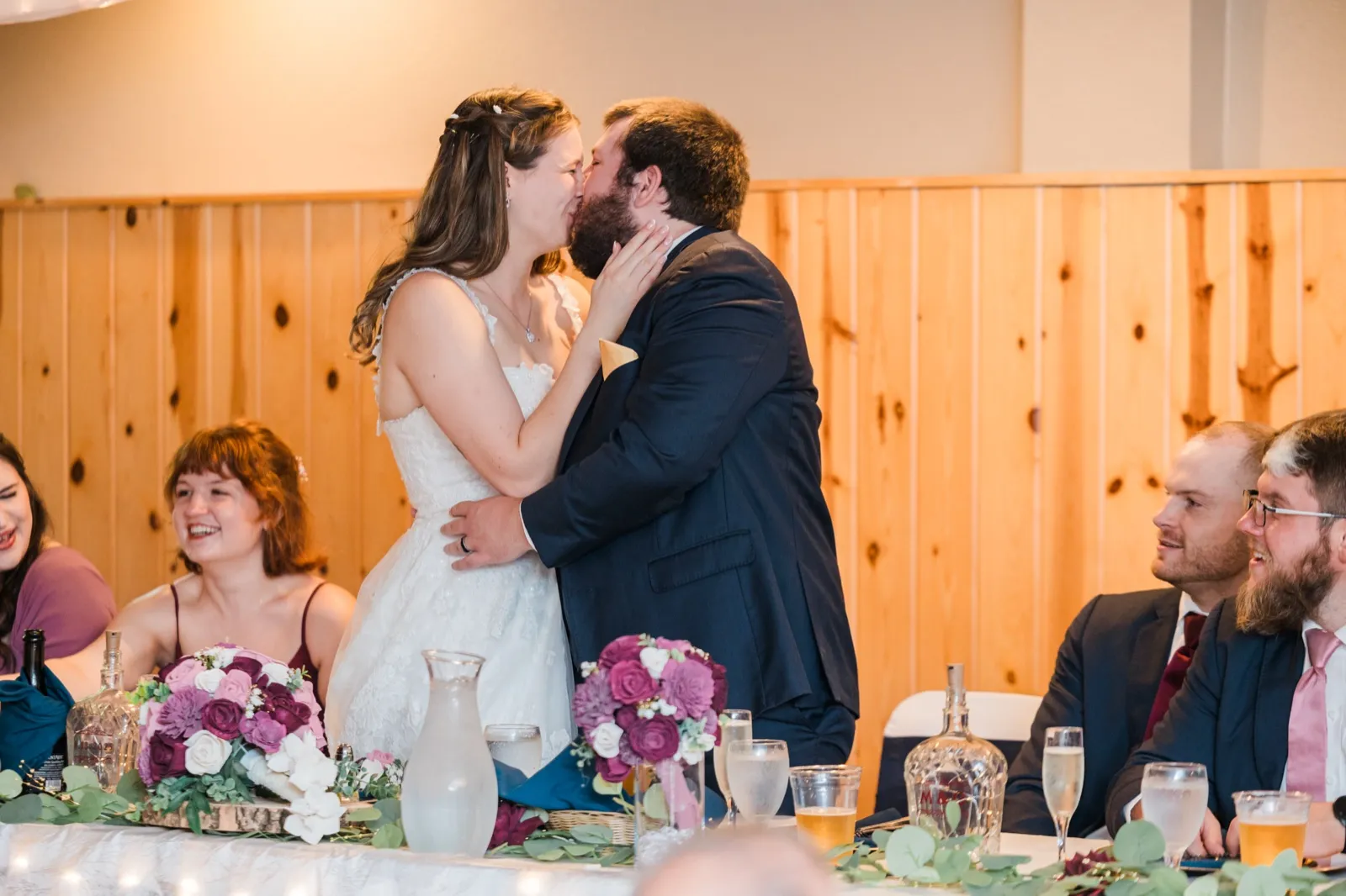 Maddie and Cody kiss at the head table during their Whitefish Lodge reception — Tim Larsen Photography, Brainerd Lakes MN