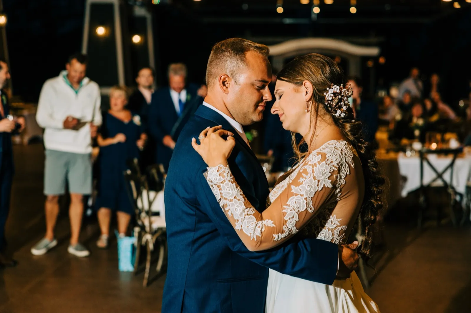 The bride and groom press their foreheads together in a quiet embrace on the dance floor as guests watch from the background. — Tim Larsen Photography, Brainerd Lakes MN
