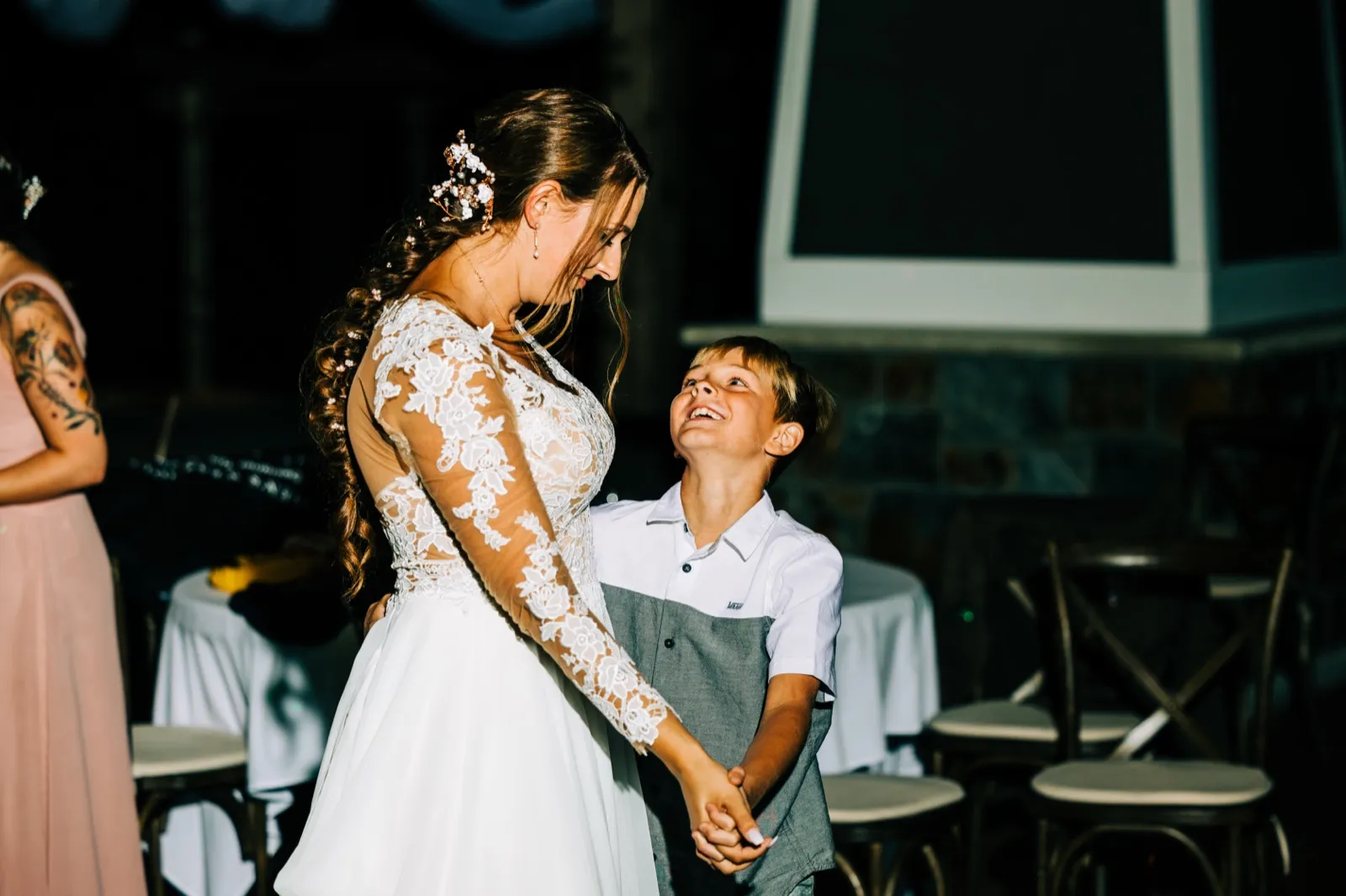 A young boy looks up smiling at the bride as they hold hands and dance together at the reception. — Tim Larsen Photography, Brainerd Lakes MN