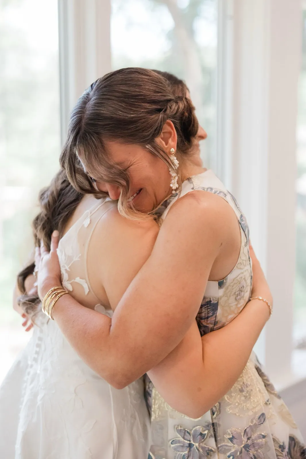 The bride and her mother hold each other in a long embrace by a bright window before the ceremony — Tim Larsen Photography, Brainerd Lakes MN