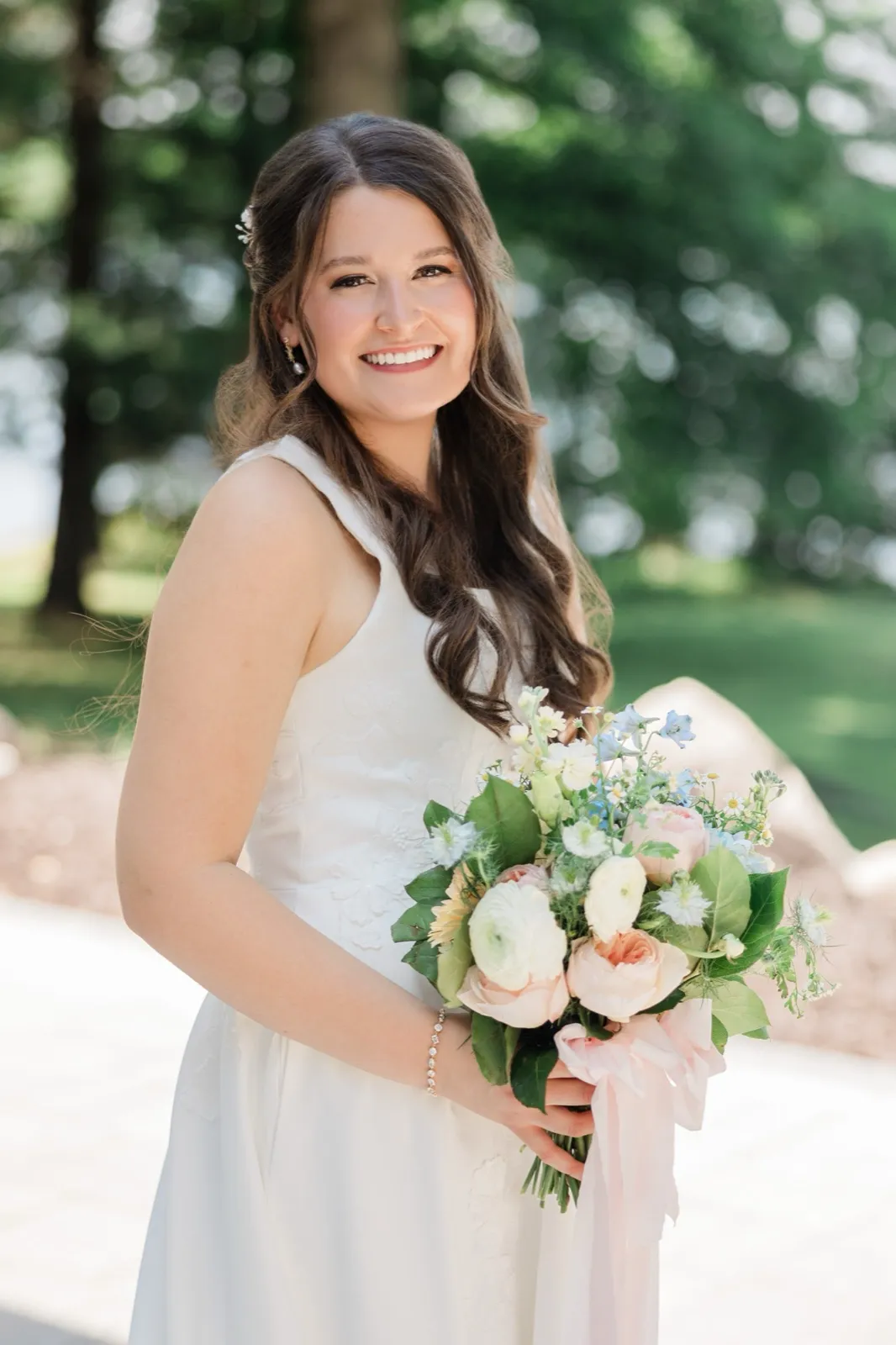 A close bridal portrait of the bride holding her bouquet, her hair catching the light against a soft green background — Tim Larsen Photography, Brainerd Lakes MN