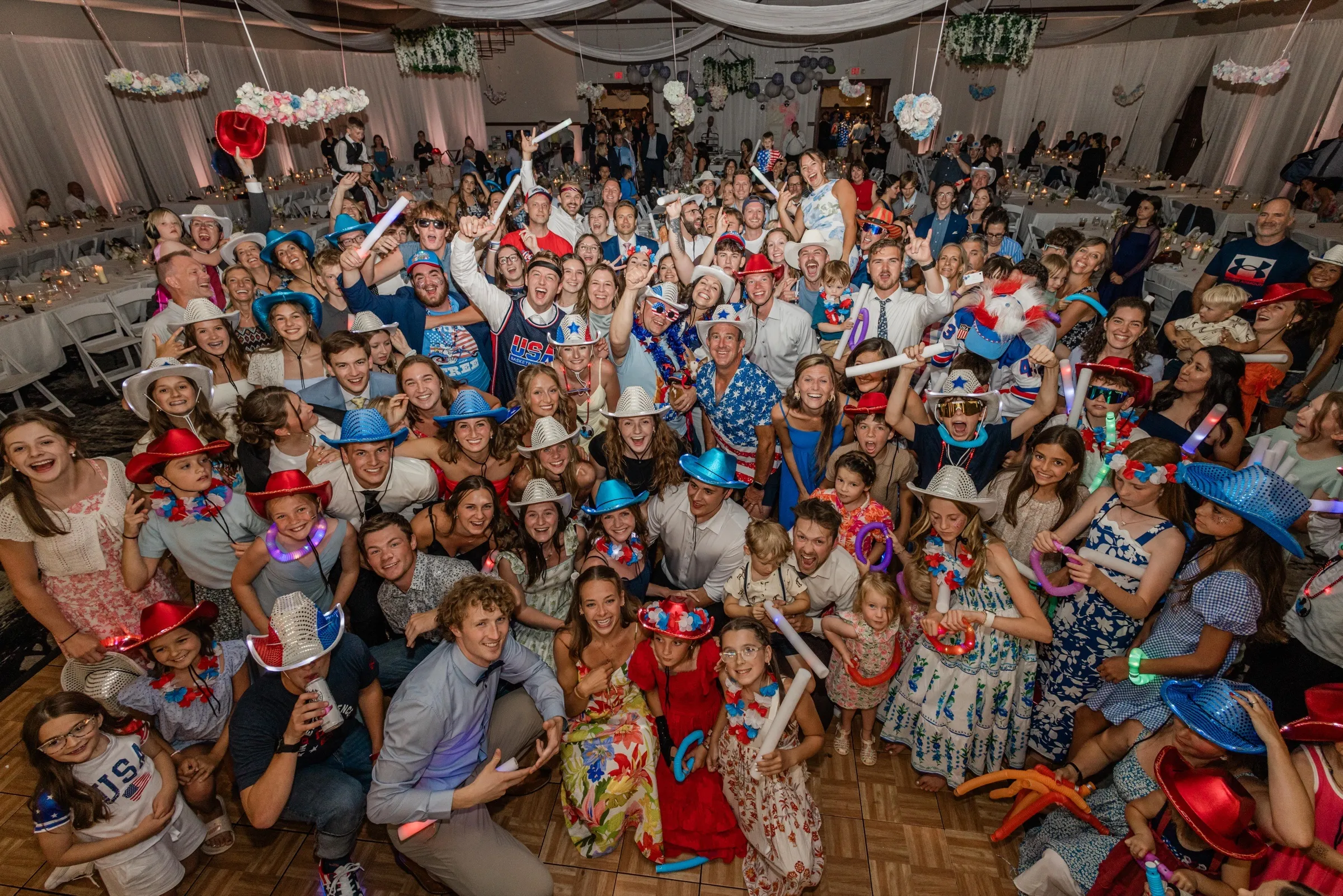 The whole guest list packs the dance floor in red, white, and blue — light-up cowboy hats, flag shirts, and glow batons — for the America-250 dance party — Tim Larsen Photography, Brainerd Lakes MN