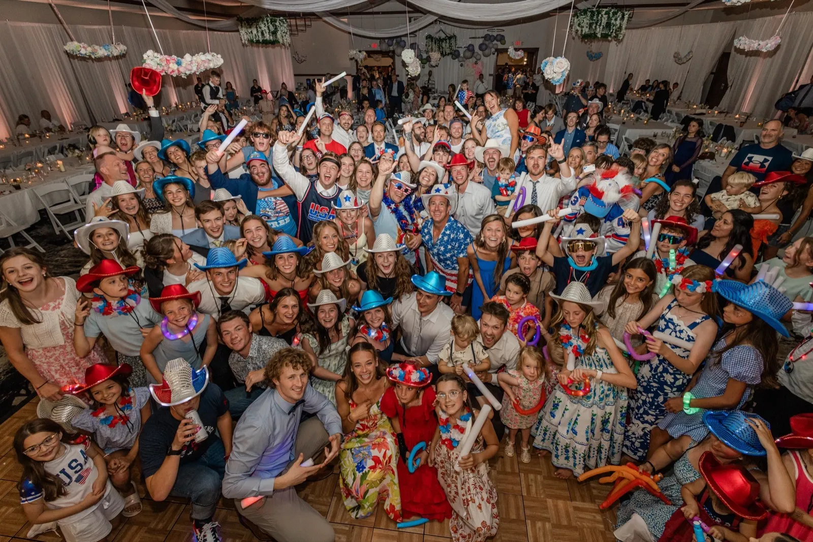 The whole guest list packs the dance floor in red, white, and blue — light-up cowboy hats, flag shirts, and glow batons — for the America-250 dance party — Tim Larsen Photography, Brainerd Lakes MN