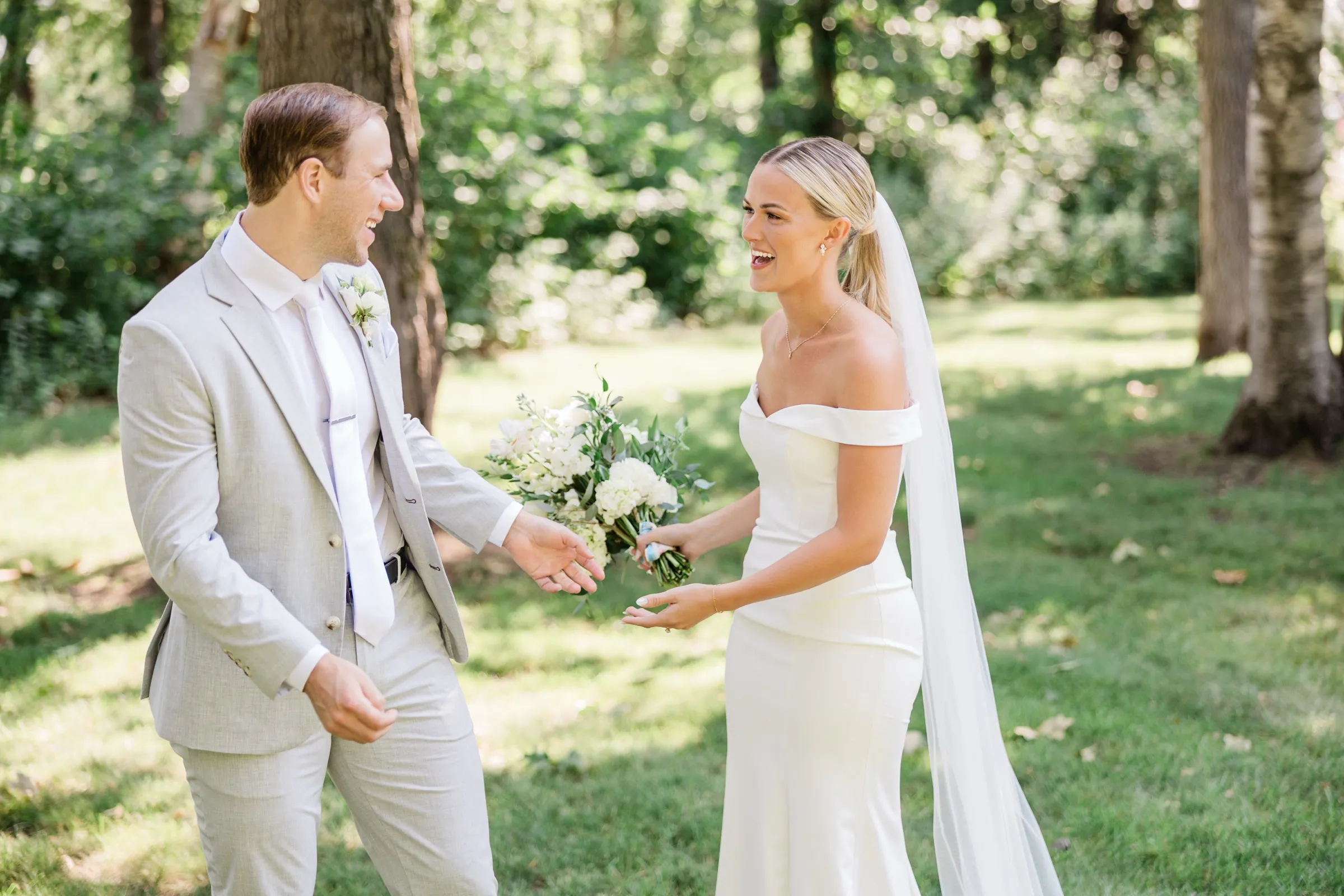 Josse and Alex laugh and reach toward each other on a shaded lawn just after their first look — Tim Larsen Photography, Brainerd Lakes MN