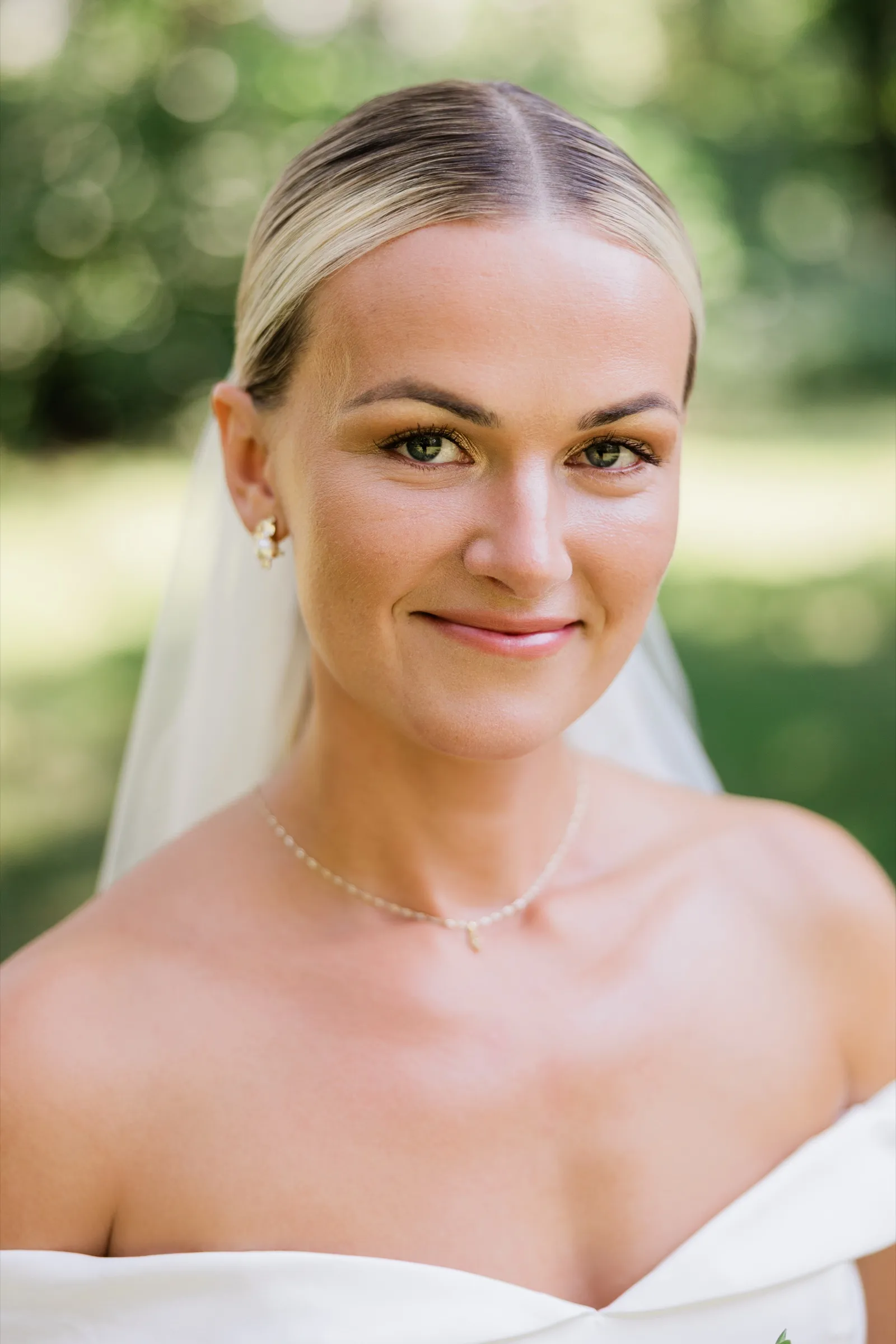 Josse in a strapless gown and veil with a slicked-back updo looks toward the camera with a slight smile — Tim Larsen Photography, Brainerd Lakes MN