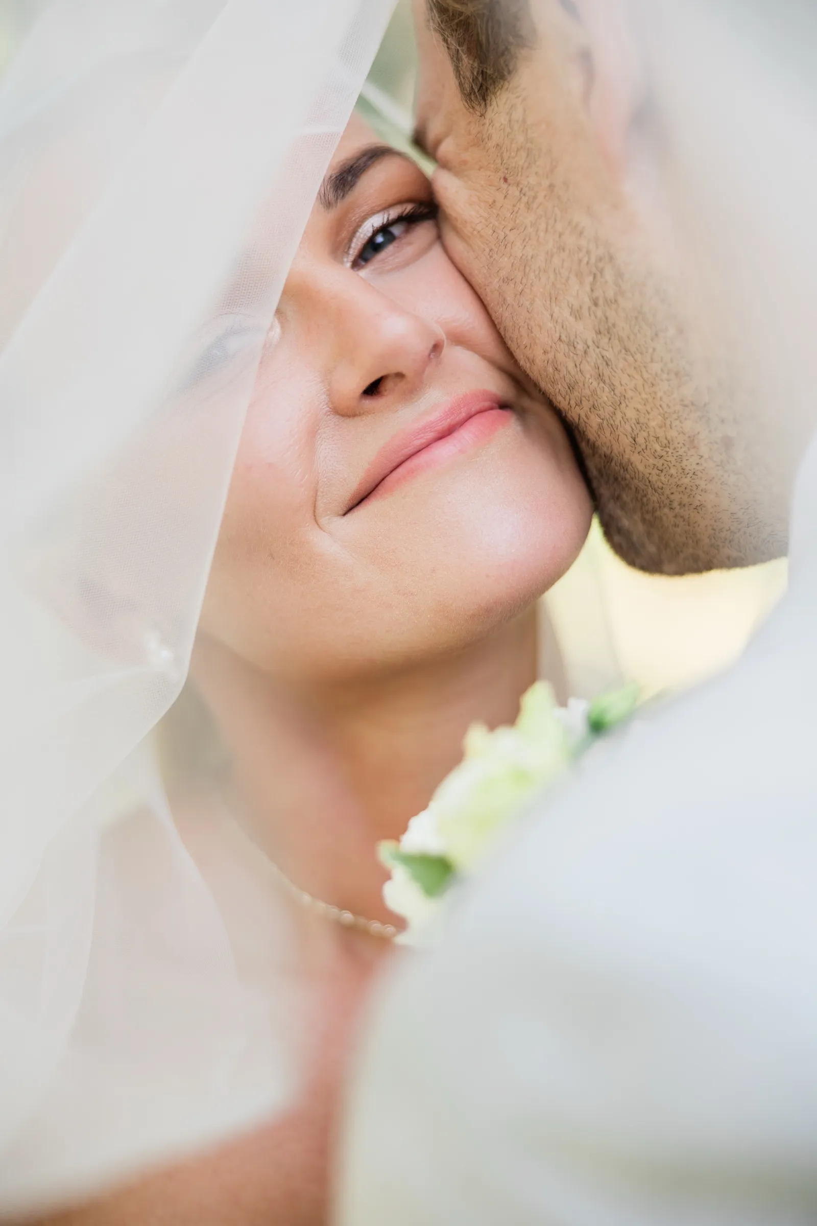 Josse's face, framed by her veil, presses cheek to cheek with Alex as she looks upward — Tim Larsen Photography, Brainerd Lakes MN
