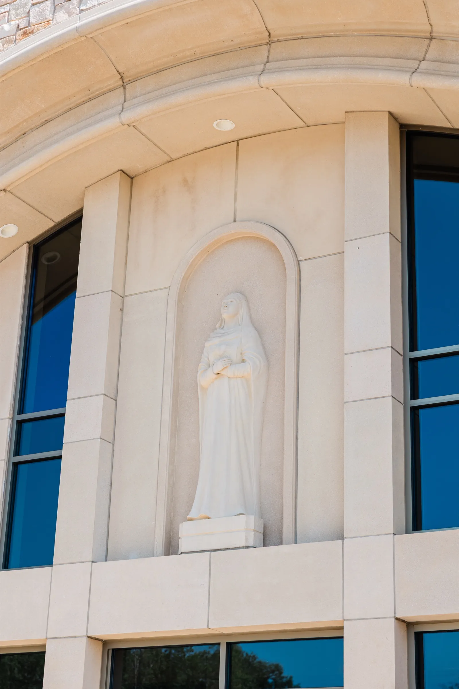 A white stone statue of the Virgin Mary in an arched niche on the limestone exterior of Immaculate Heart Catholic Church in Crosslake — Tim Larsen Photography, Brainerd Lakes MN
