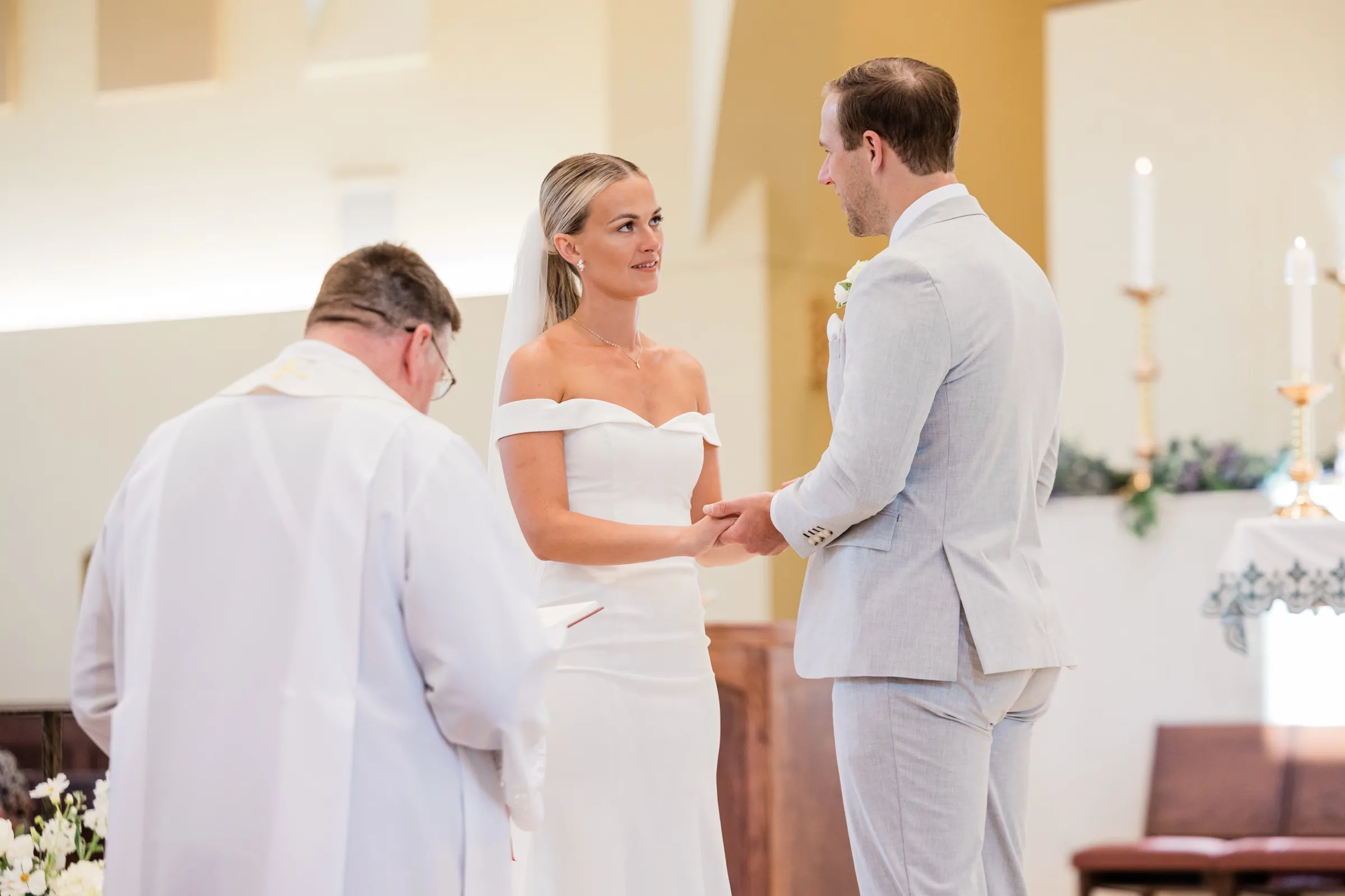 Josse holds Alex's hands and looks up at him during their vows at the altar — Tim Larsen Photography, Brainerd Lakes MN