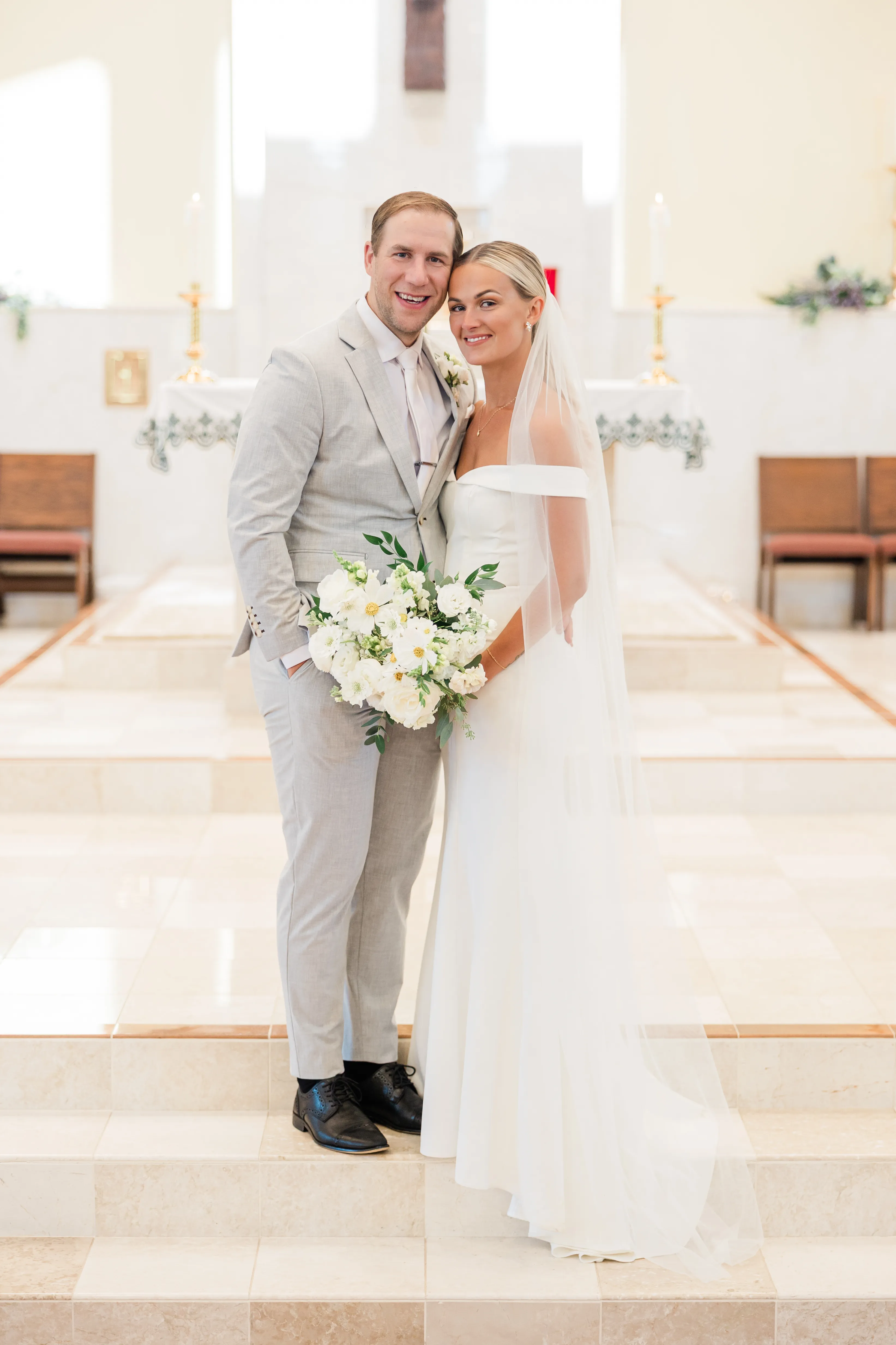 Josse and Alex stand together on the altar steps of Immaculate Heart Catholic Church after the ceremony — Tim Larsen Photography, Brainerd Lakes MN