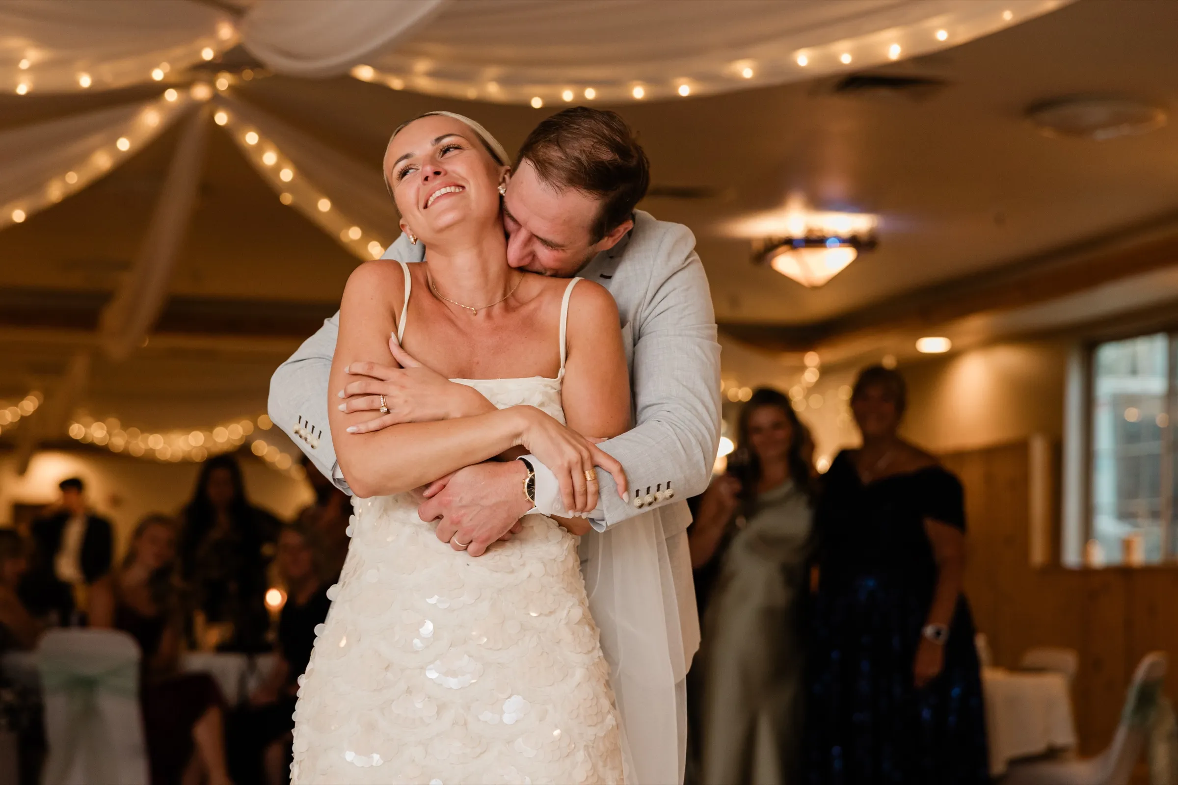Alex wraps his arms around Josse from behind and presses his face to her neck as she tilts her head back laughing on the dance floor — Tim Larsen Photography, Brainerd Lakes MN