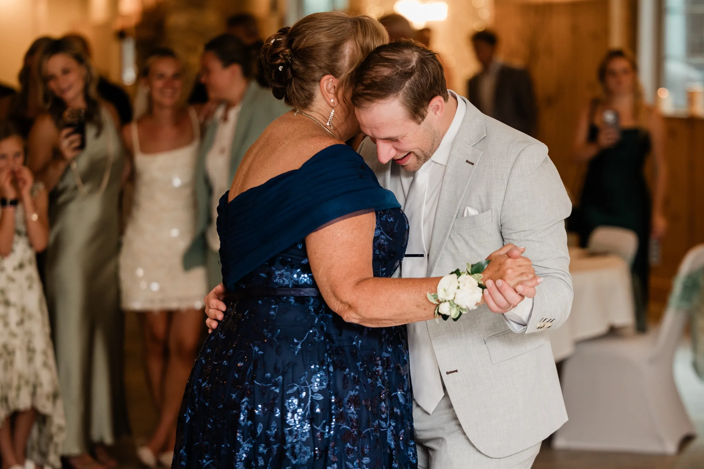 Alex rests his head against his mother's as they dance, his face crumpling with emotion while guests watch from the edge of the floor — Tim Larsen Photography, Brainerd Lakes MN