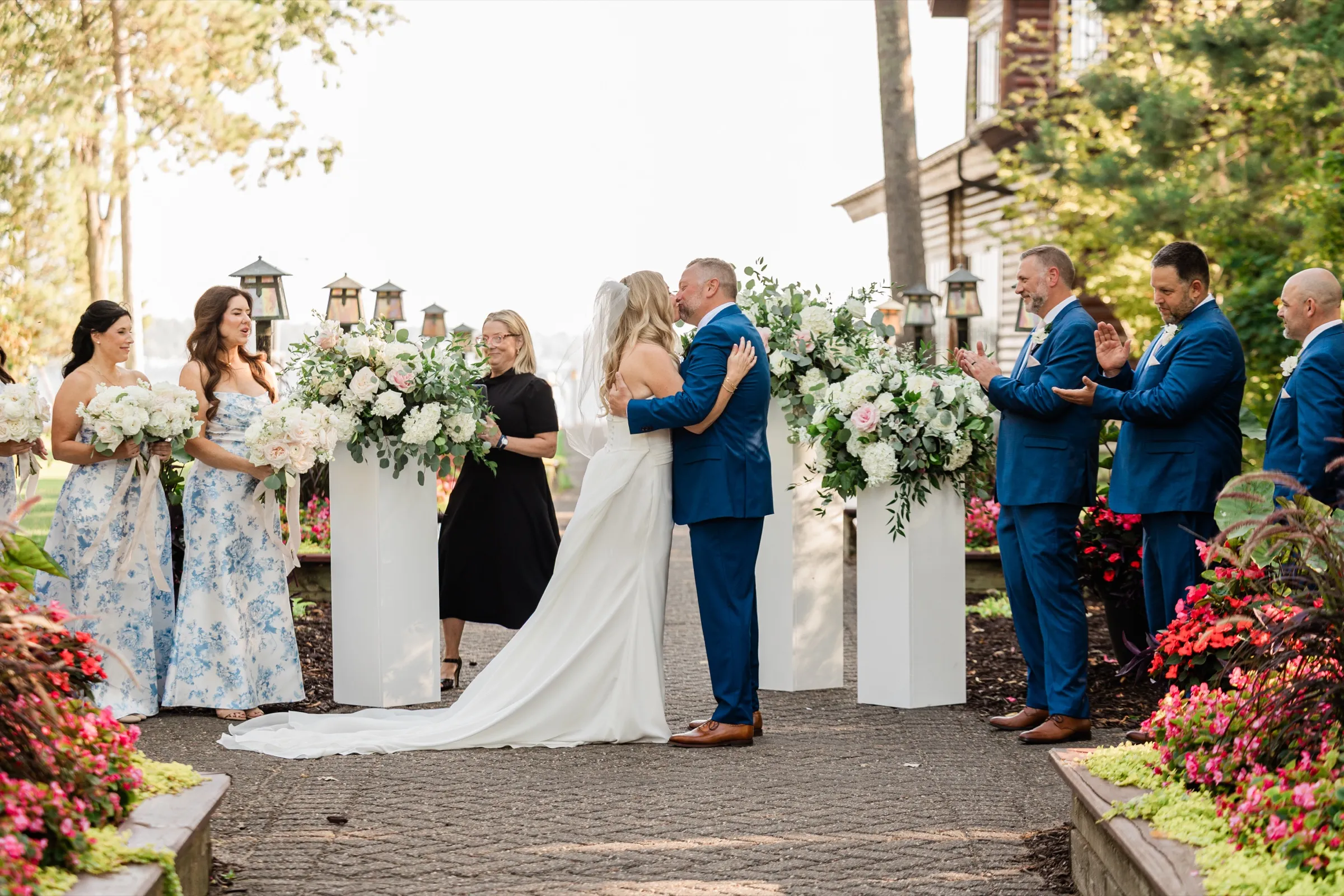 The couple kiss at the center of the aisle while the bridesmaids and groomsmen applaud from either side. — Tim Larsen Photography, Brainerd Lakes MN
