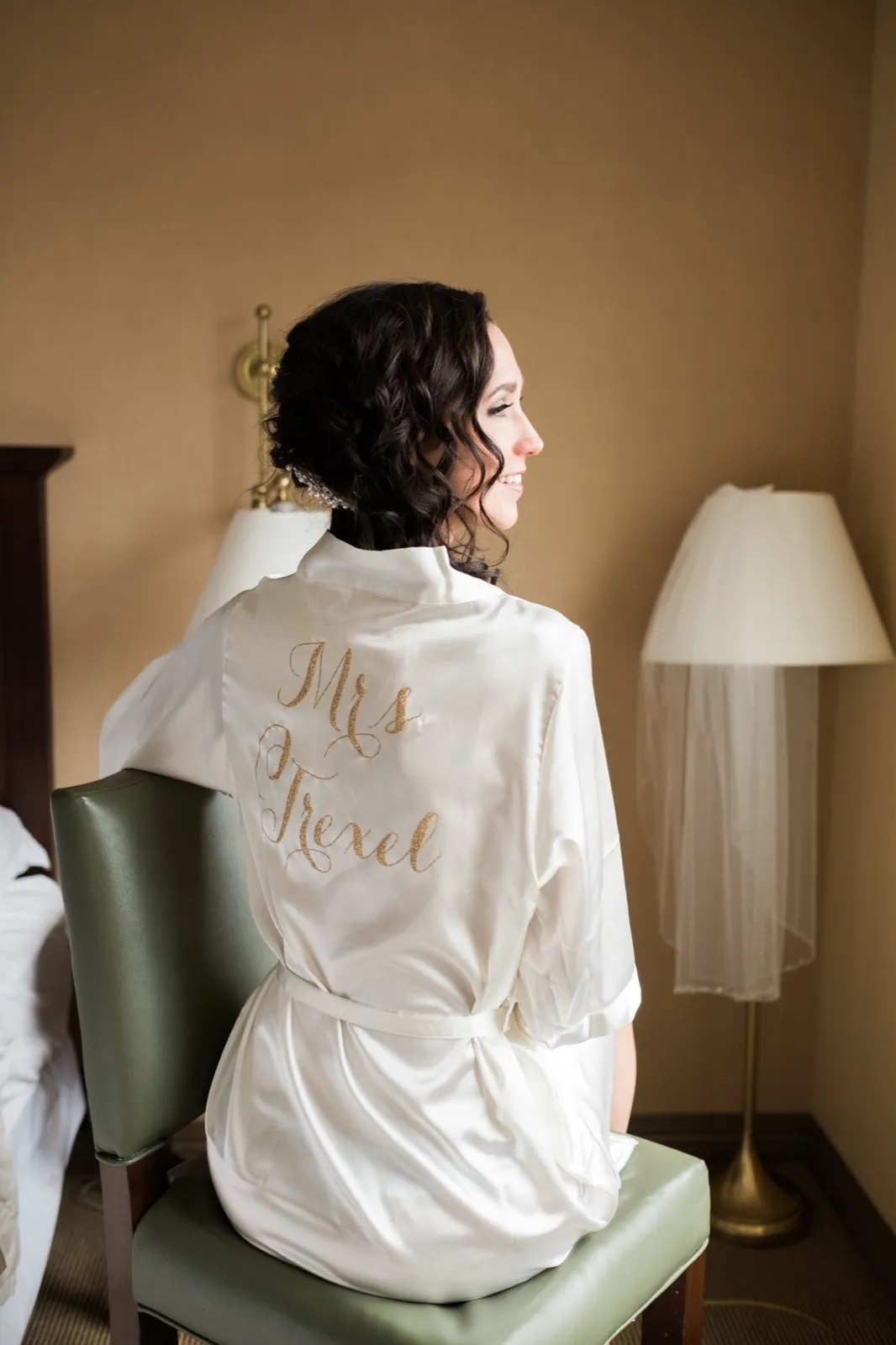 Bride seated in profile in her custom Mrs Trexel robe, veil on a stand beside her in the Greysolon Plaza bridal suite — autumn wedding morning — Tim Larsen Photography, Duluth MN
