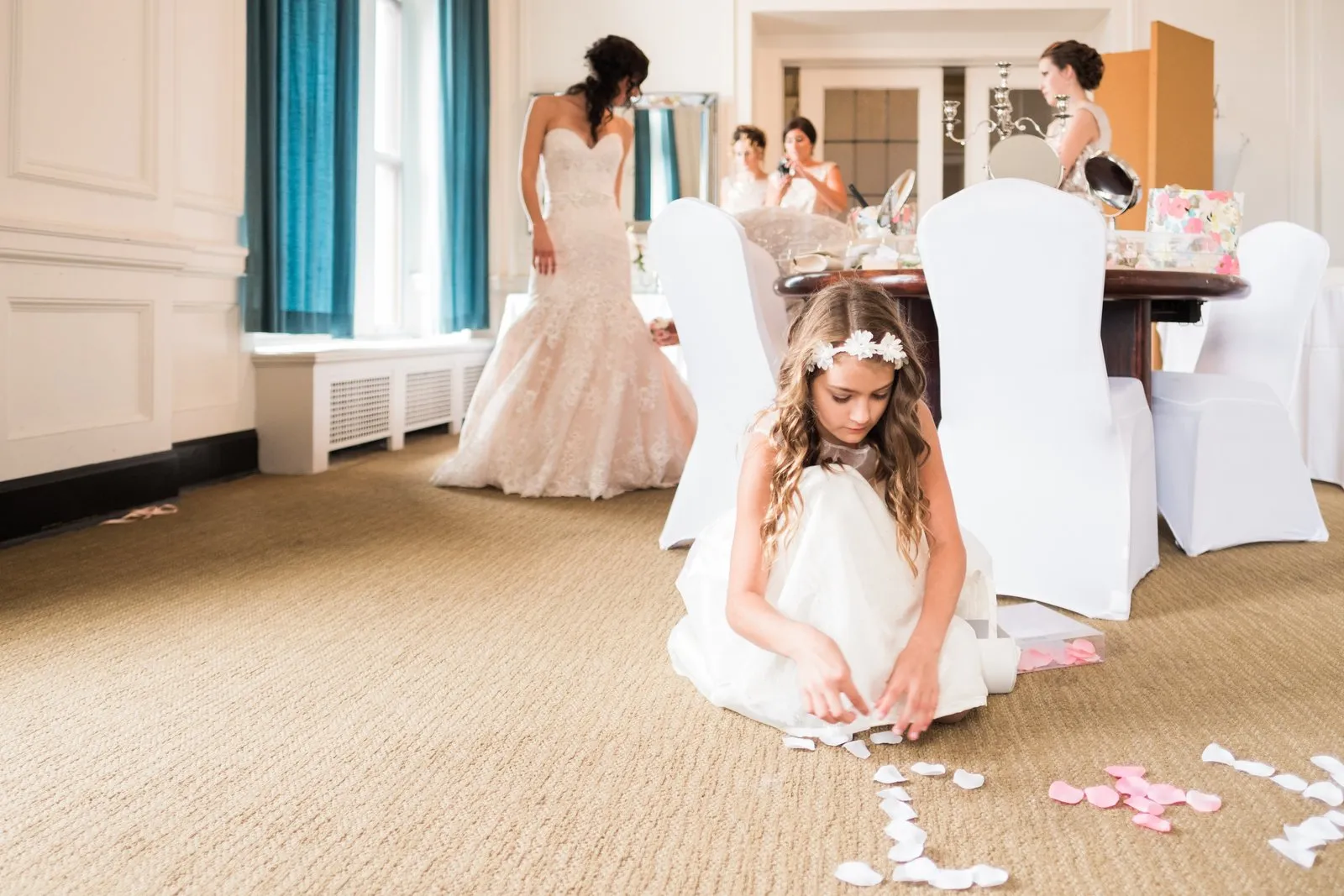 Flower girl foregrounded with scattered petals as the bride and bridal party gather behind in the Greysolon Plaza bridal suite — Tim Larsen Photography, Duluth MN