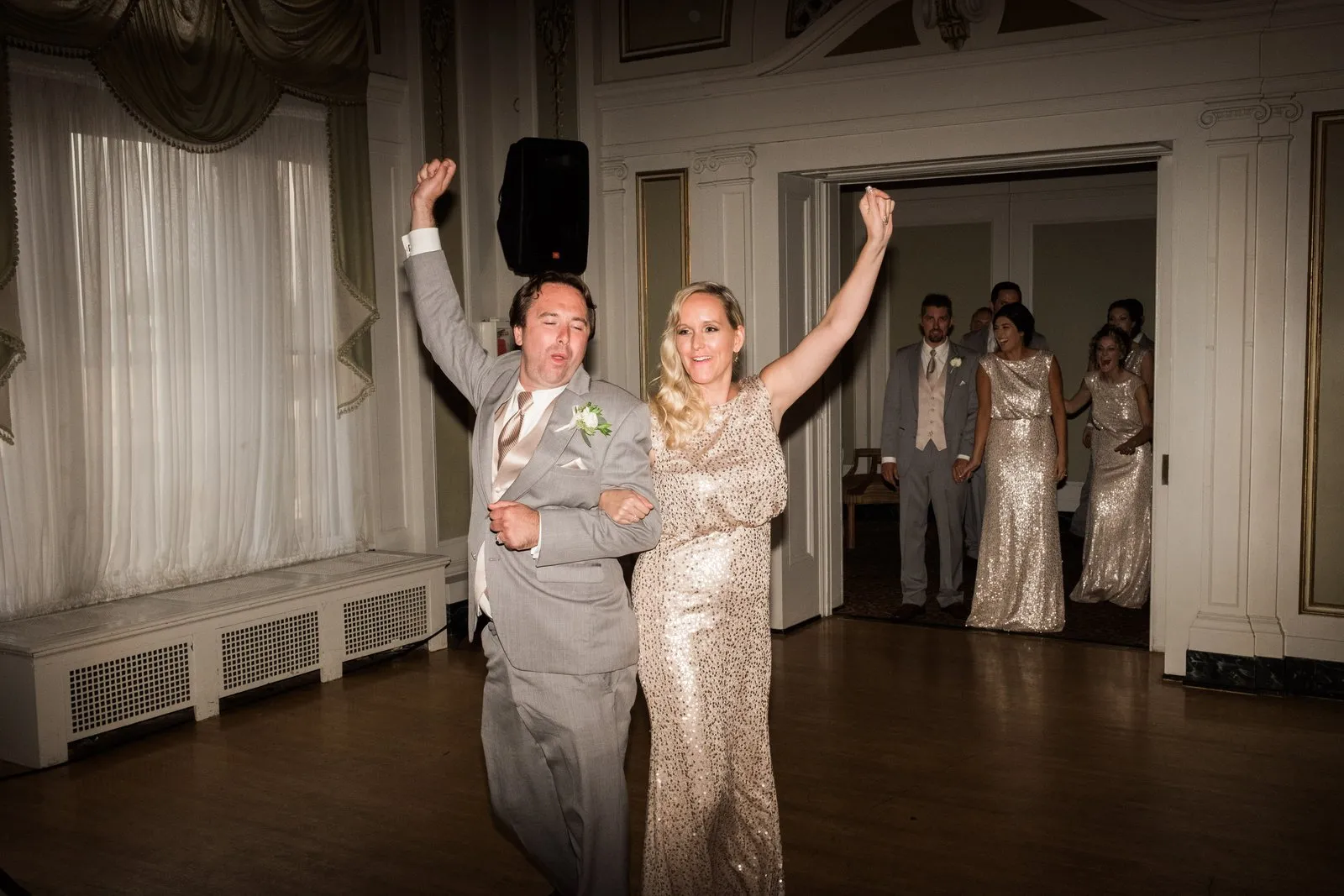 Bride and groom mid-cheer at the grand entrance, bridal party framed in the ornate Greysolon Ballroom doorway behind them — Tim Larsen Photography, Duluth MN