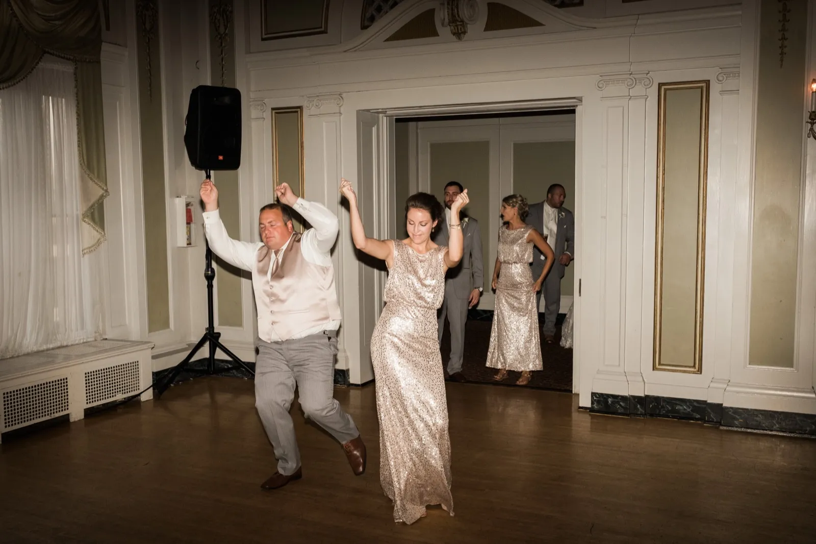Open dance floor energy — two guests mid-pose under the ornate Greysolon Ballroom architecture, doorway framing other bridal party members behind — Tim Larsen Photography, Duluth MN