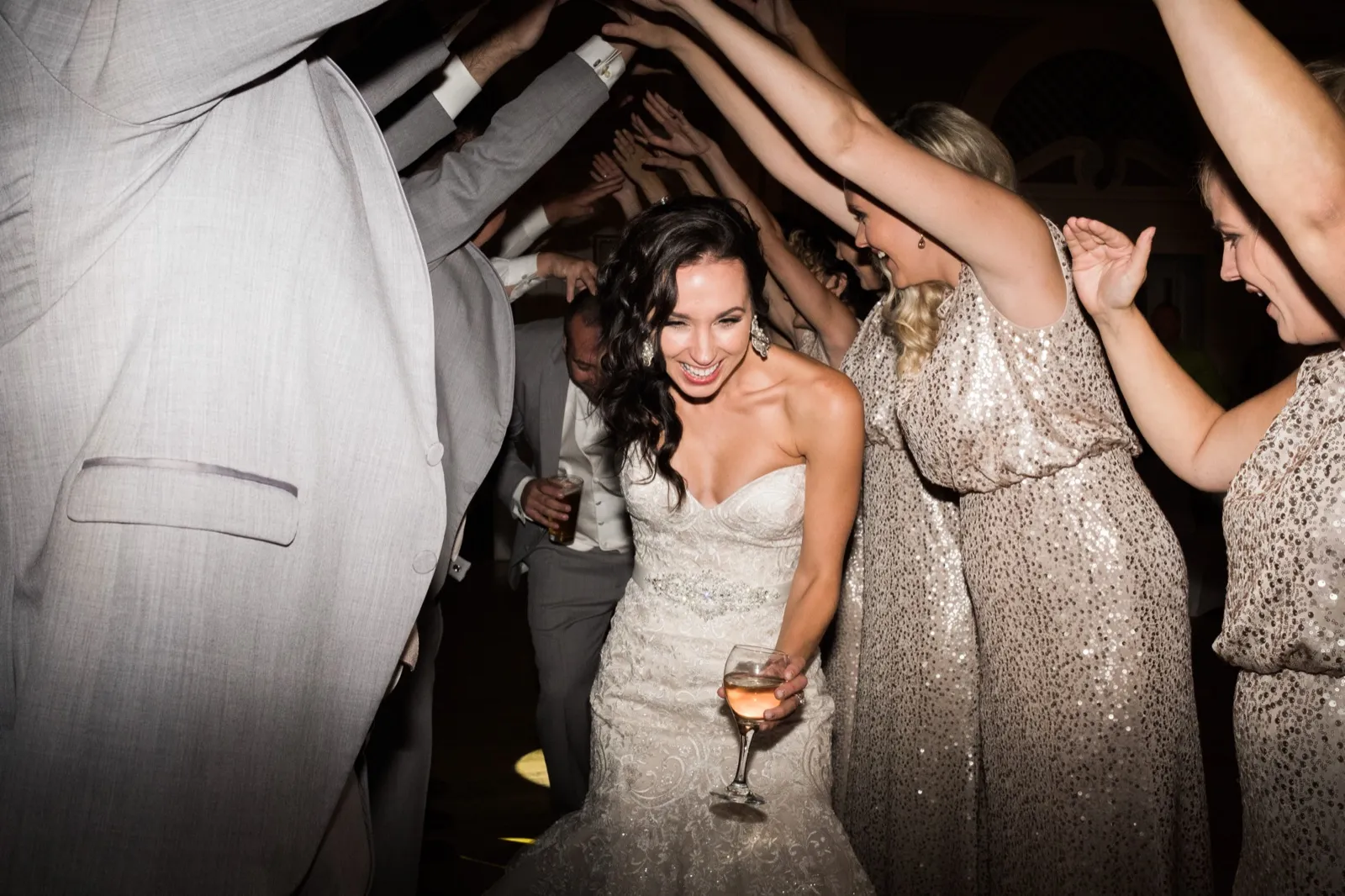 Bride centered under a tunnel of raised arms on the Greysolon Ballroom dance floor, champagne glass in hand — Tim Larsen Photography, Duluth MN