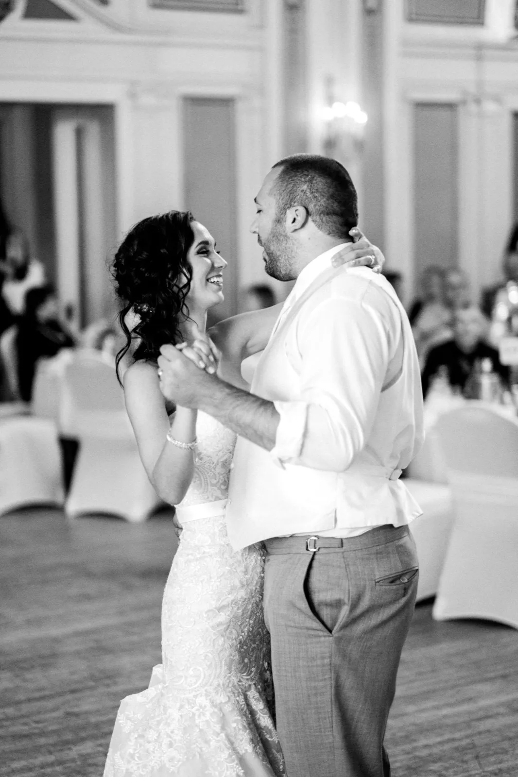 Bride’s joyful upward gaze anchors the frame during the first dance — Greysolon Ballroom architecture and guest tables receding behind — Tim Larsen Photography, Duluth MN