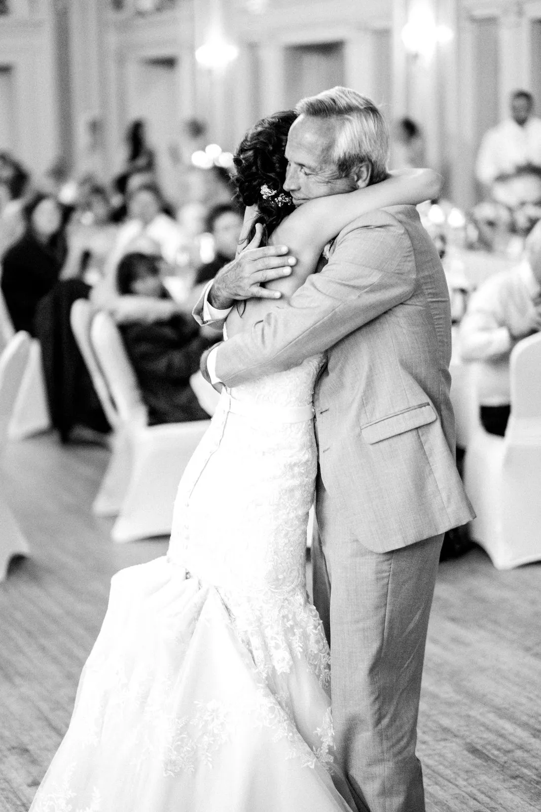 Centered parent dance embrace under the Greysolon Ballroom chandeliers, seated guests softly out of focus framing the moment — Tim Larsen Photography, Duluth MN