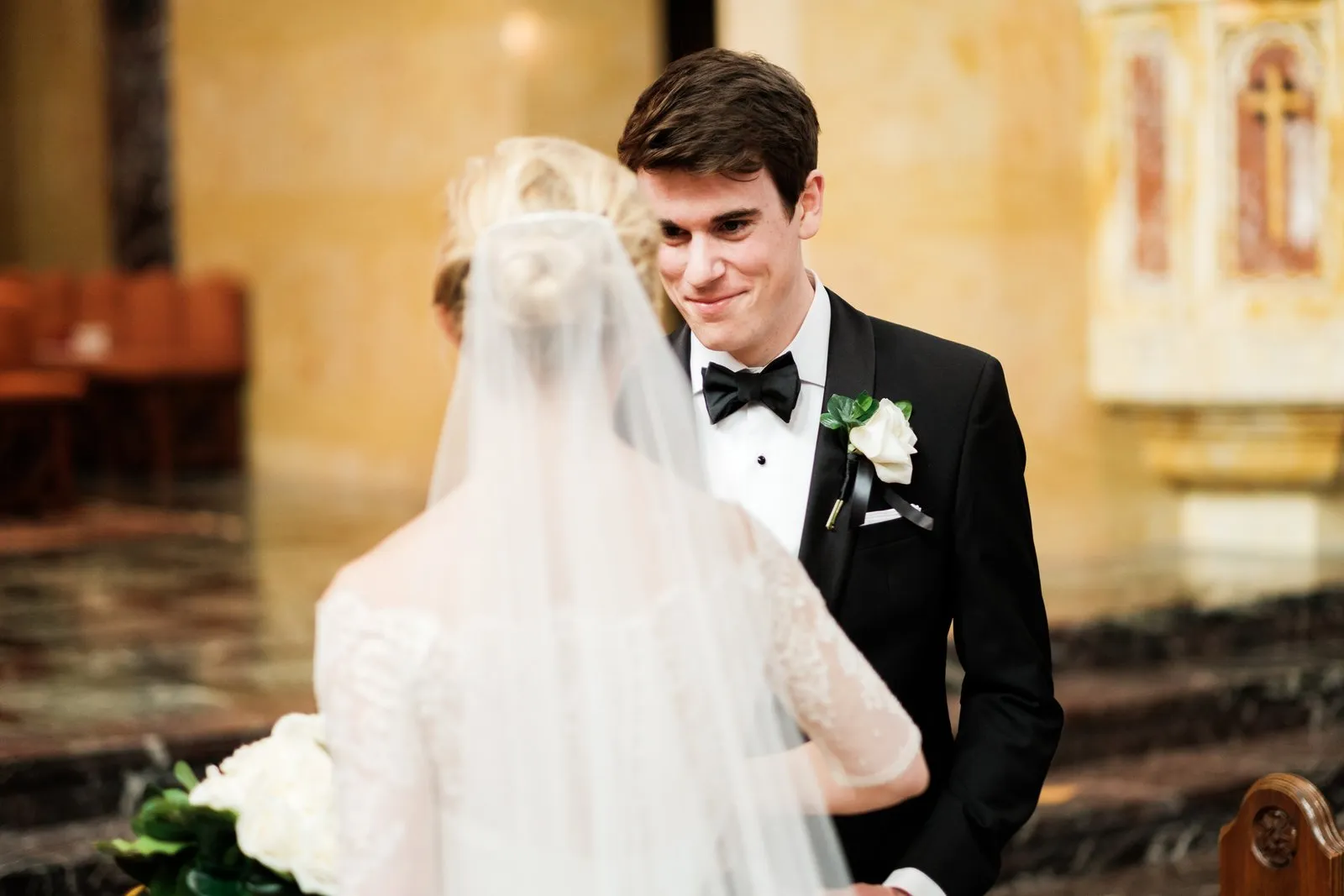 The groom smiles softly at his veiled bride during the ceremony inside the warm marble Cathedral of Our Lady of the Rosary — Tim Larsen Photography, Duluth MN