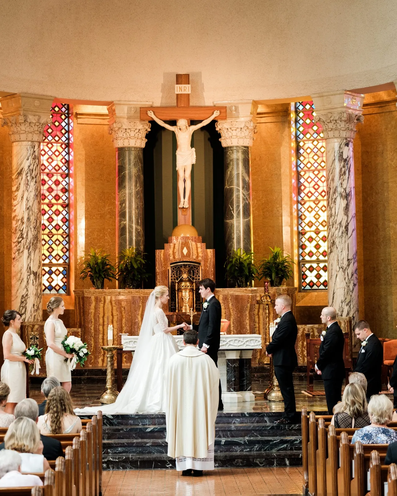 The bride and groom exchange vows at the marble altar beneath the crucifix and stained glass of the Cathedral of Our Lady of the Rosary in Duluth — Tim Larsen Photography