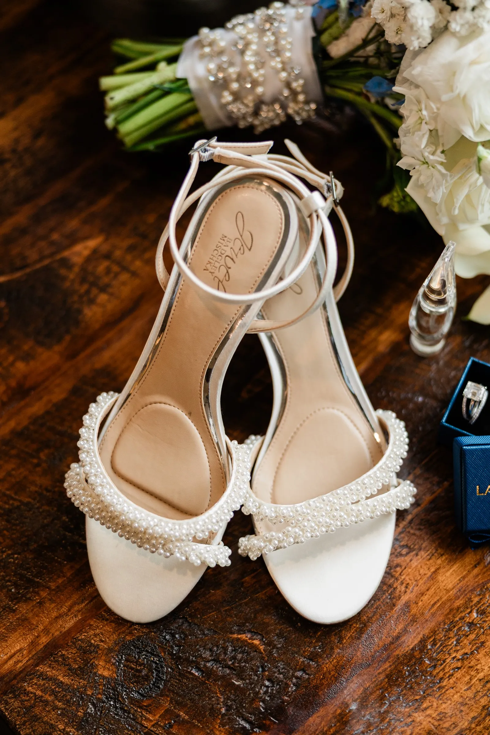 Pearl-trimmed bridal shoes beside Lauren’s bouquet on a wooden table — Tim Larsen Photography, Brainerd Lakes MN