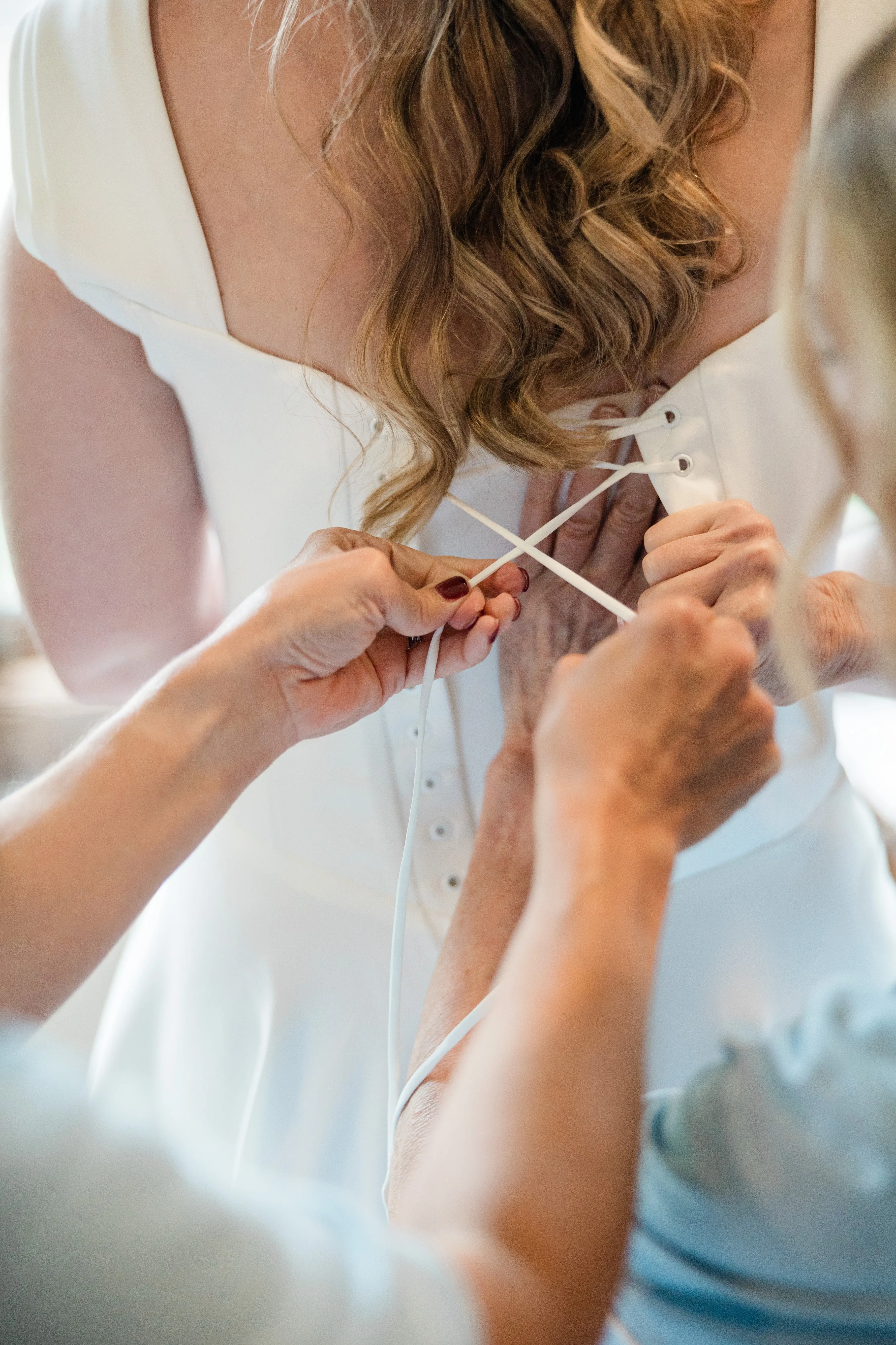 Hands lace the back of Lauren’s wedding gown in the Garden Cottages — Tim Larsen Photography, Brainerd Lakes MN