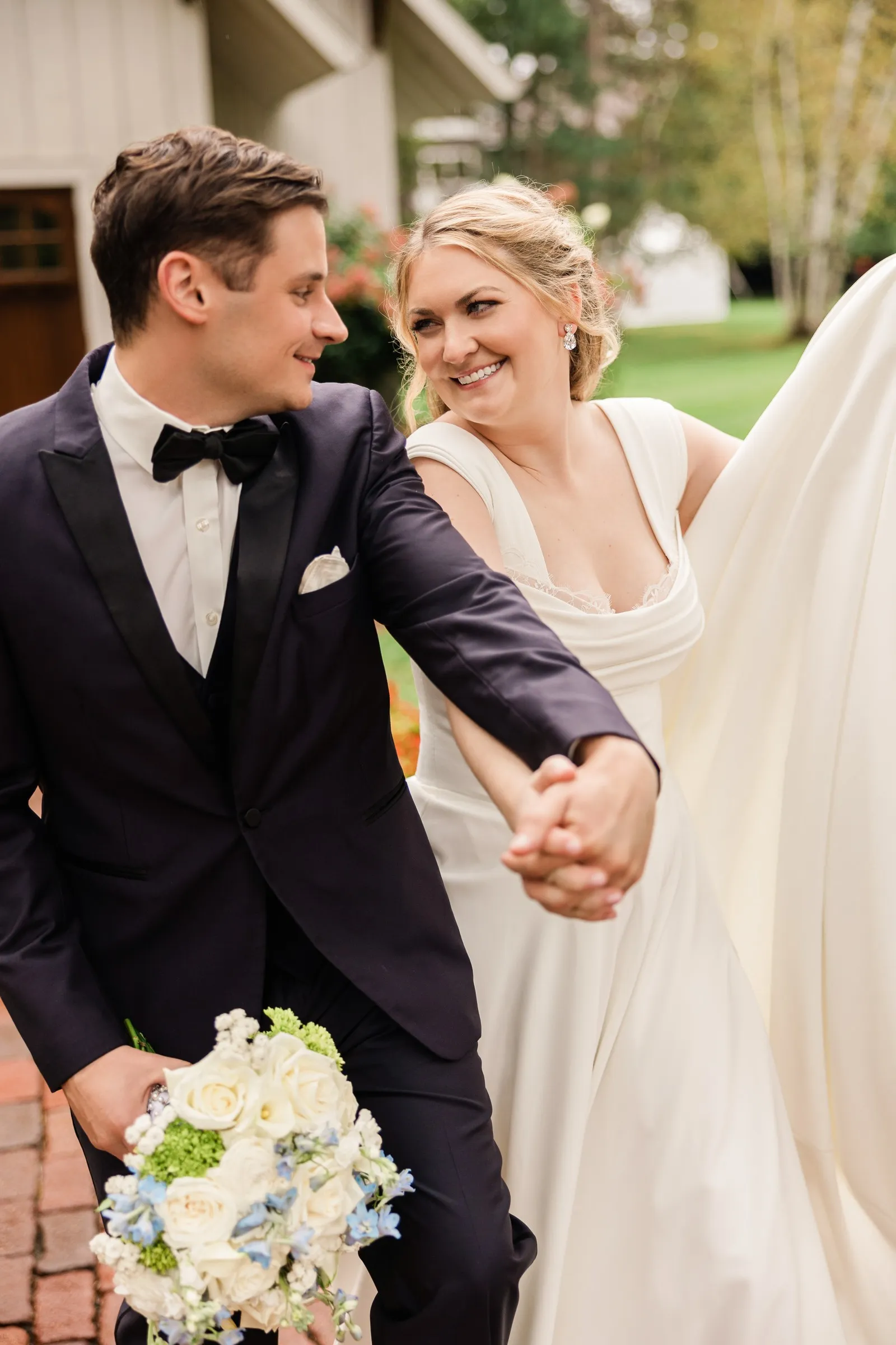 Lauren and Noah smile at each other while walking hand in hand outside the Chapel — Tim Larsen Photography, Brainerd Lakes MN
