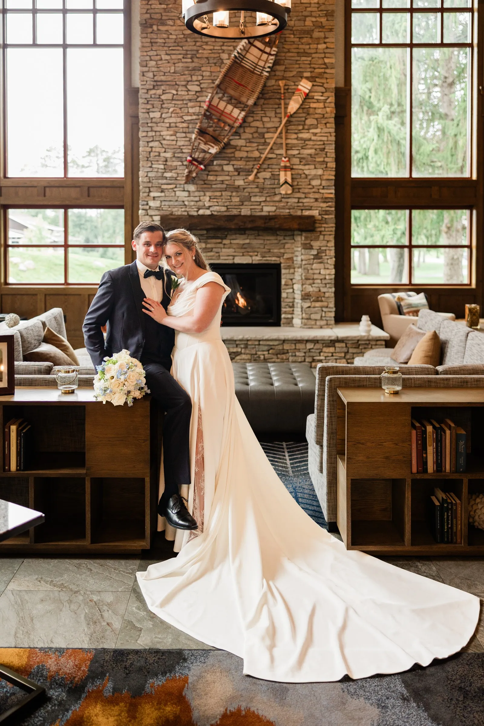 Lauren and Noah embrace in front of a stone fireplace with a canoe mounted above it — Tim Larsen Photography, Brainerd Lakes MN